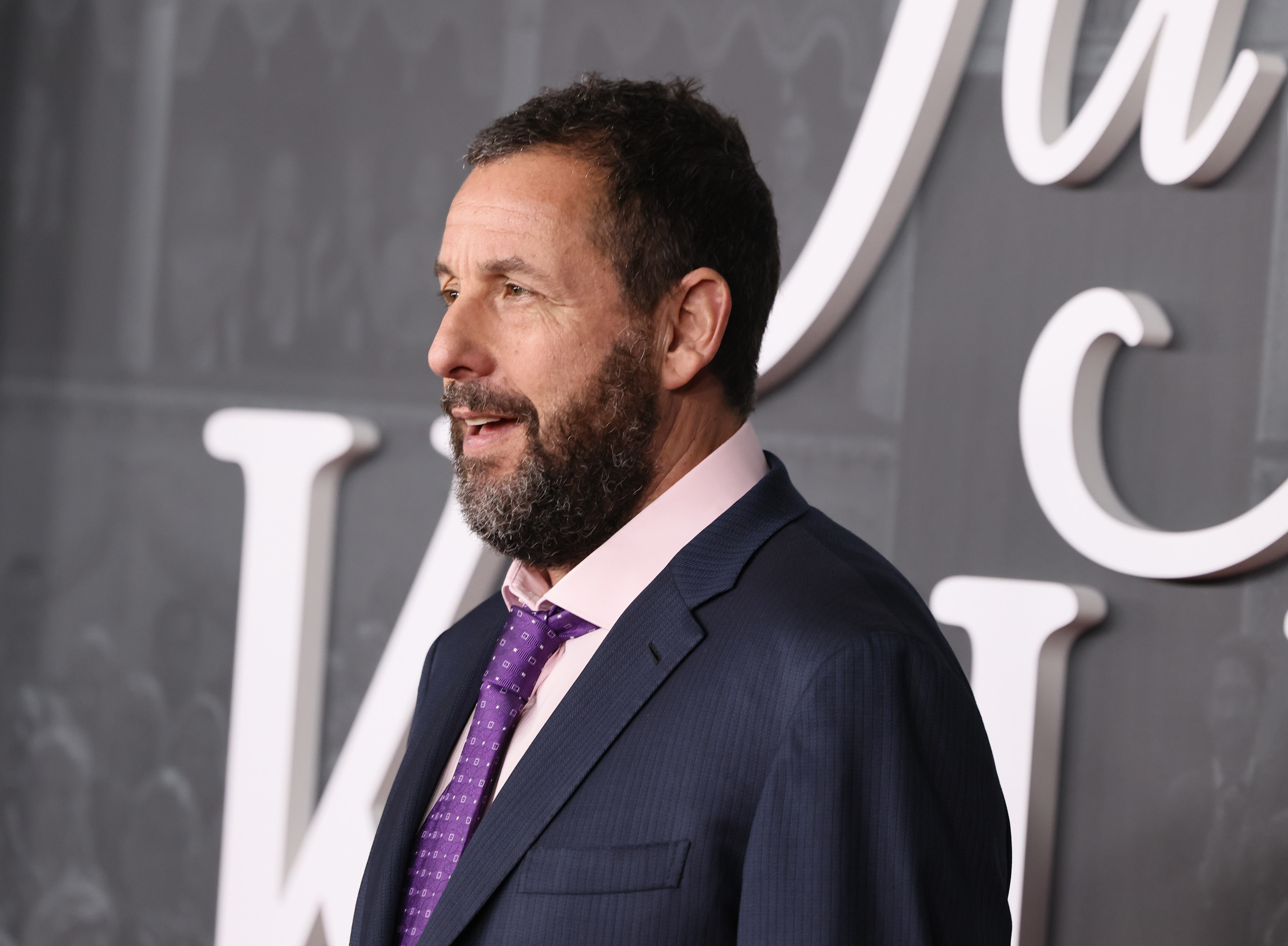 At the premiere of Netflix’s "Jay Kelly," Adam Sandler owns the red carpet in this side shot. The Hollywood A-lister is effortlessly commanding attention with his presence.
