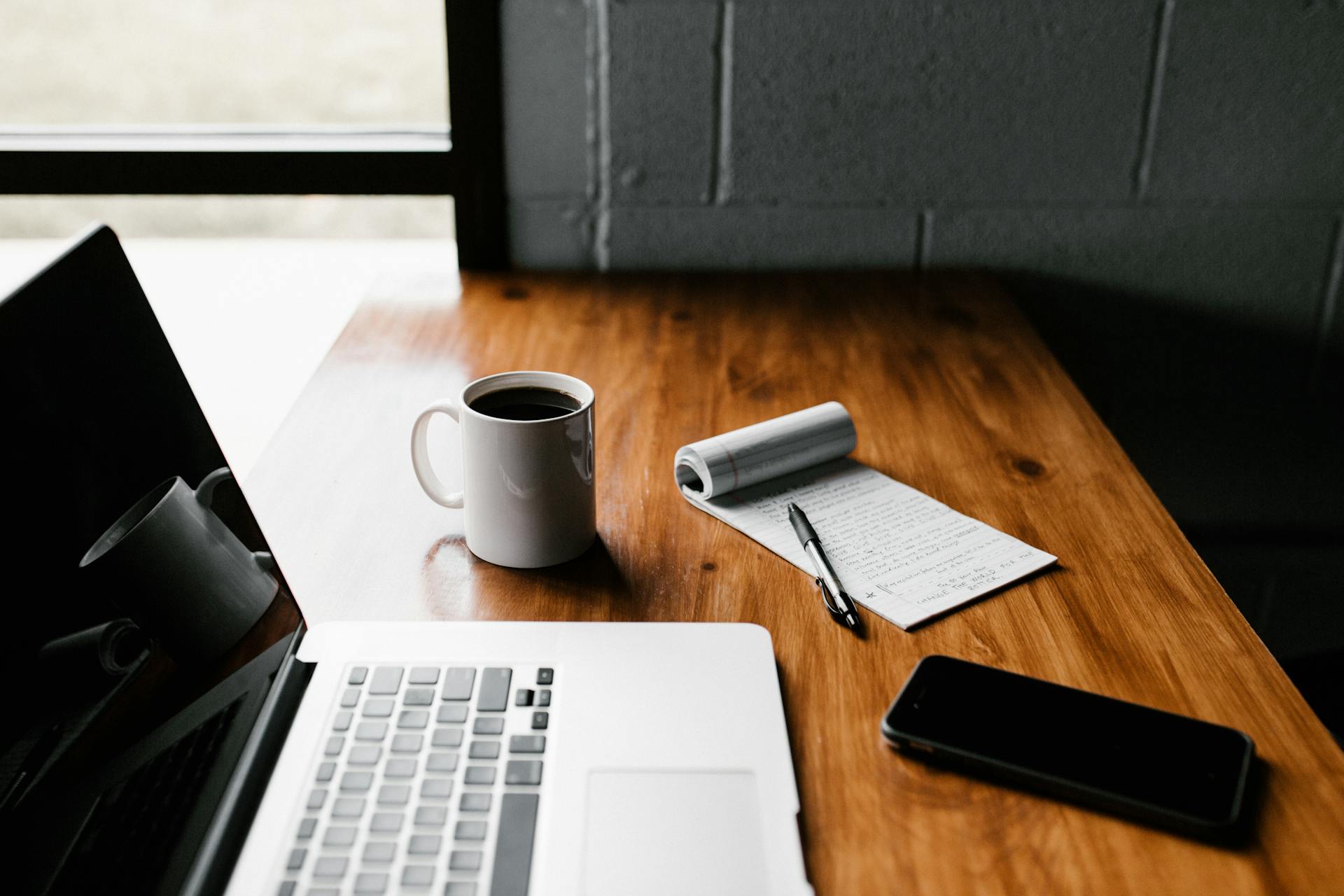 A laptop on a table with a notebook and cell phone | Source: Pexels