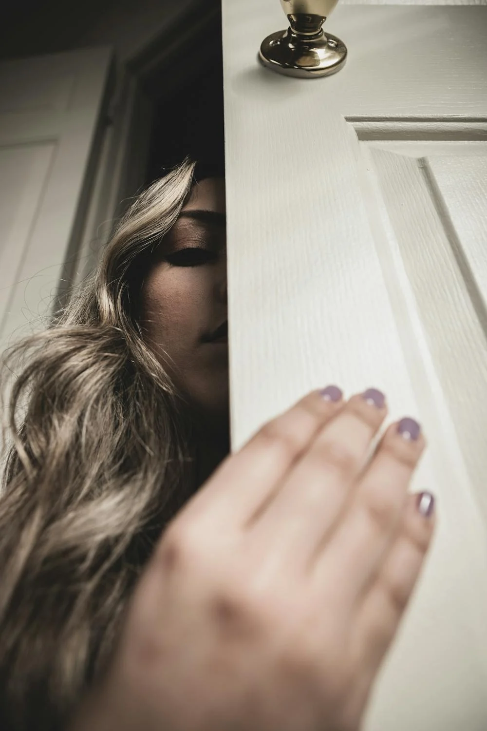 A woman peeking behind a door | Source: Pexels