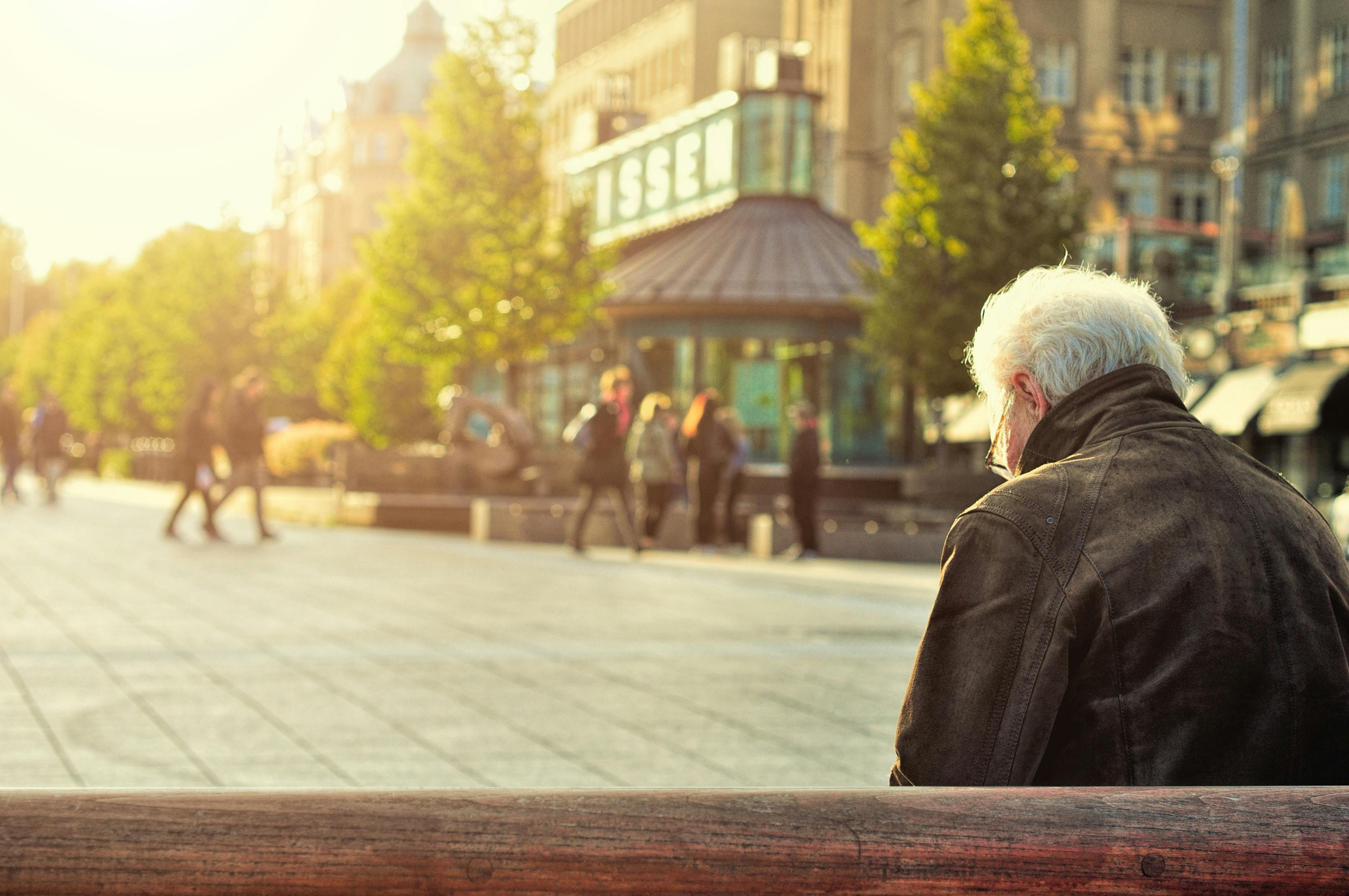 A person sitting on a wooden bench wearing a black leather jacket | Source: Pexels