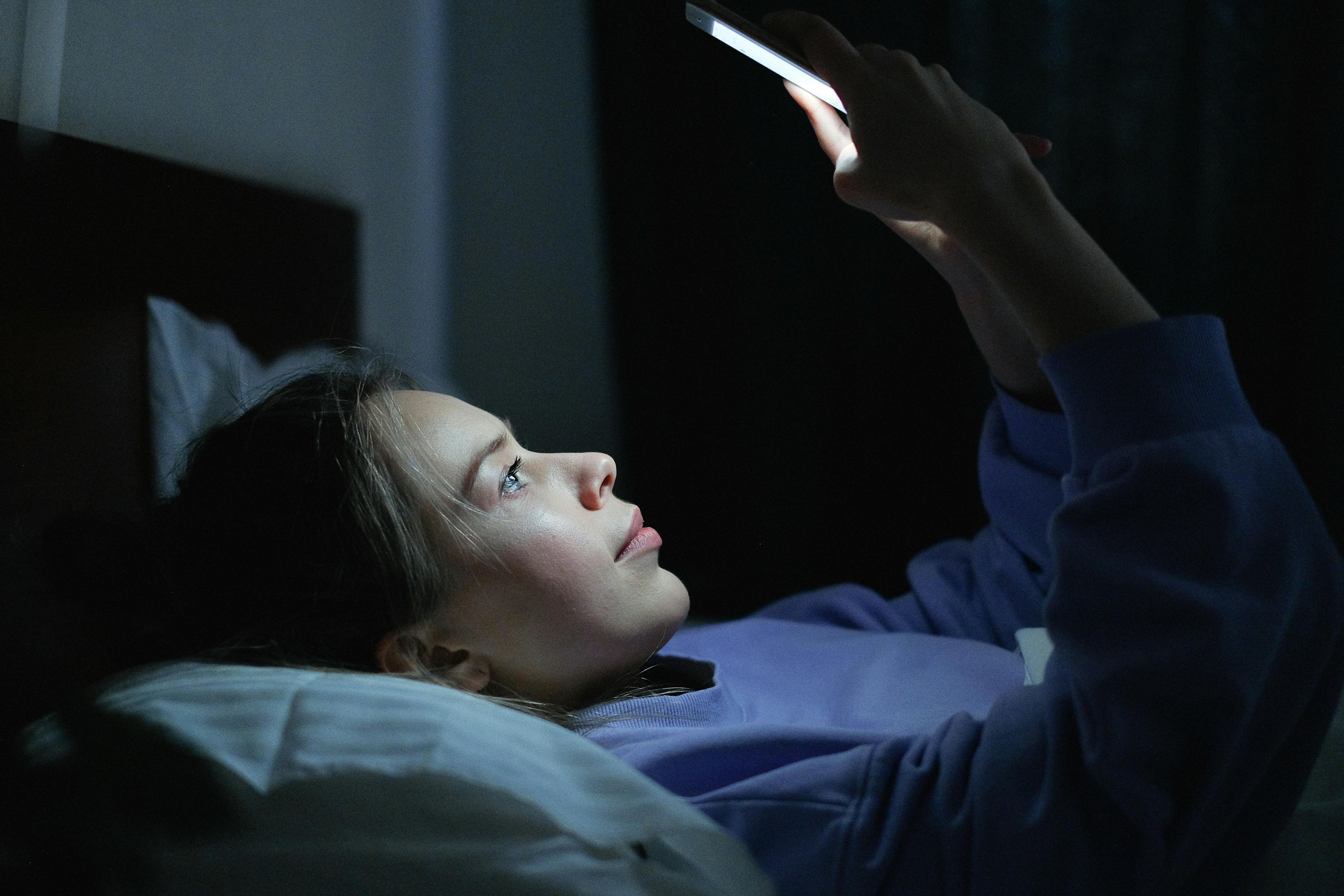 Woman checking her phone while on bed | Source: Pexels