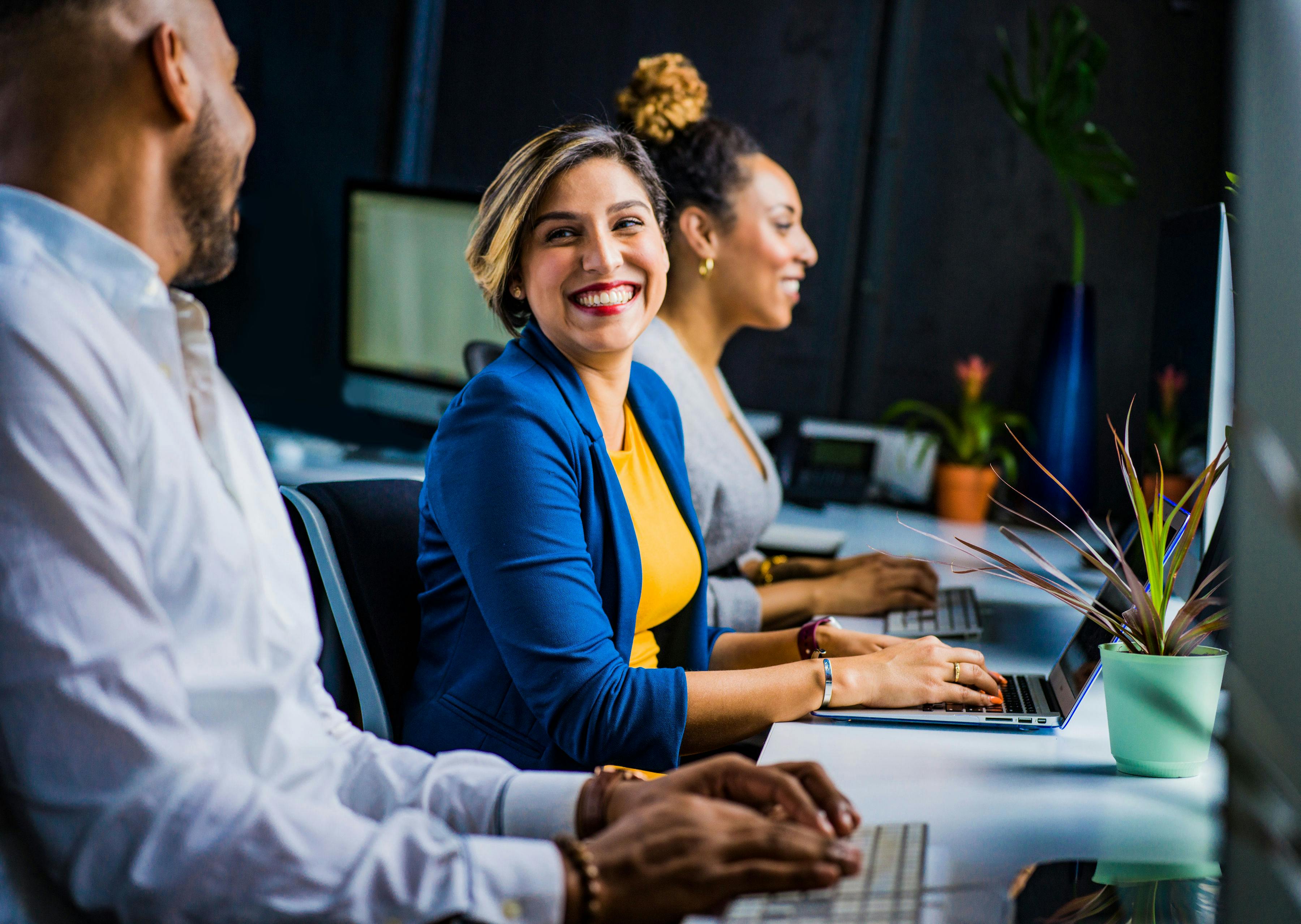 Woman smiling next to colleagues | Source: Pexels