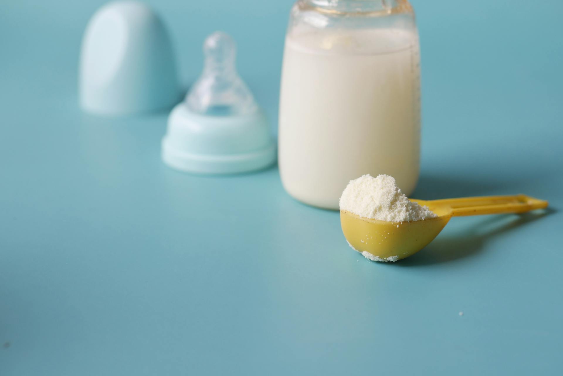 A close-up shot of a baby's feeder and a spoonful of formula milk powder | Source: Pexels