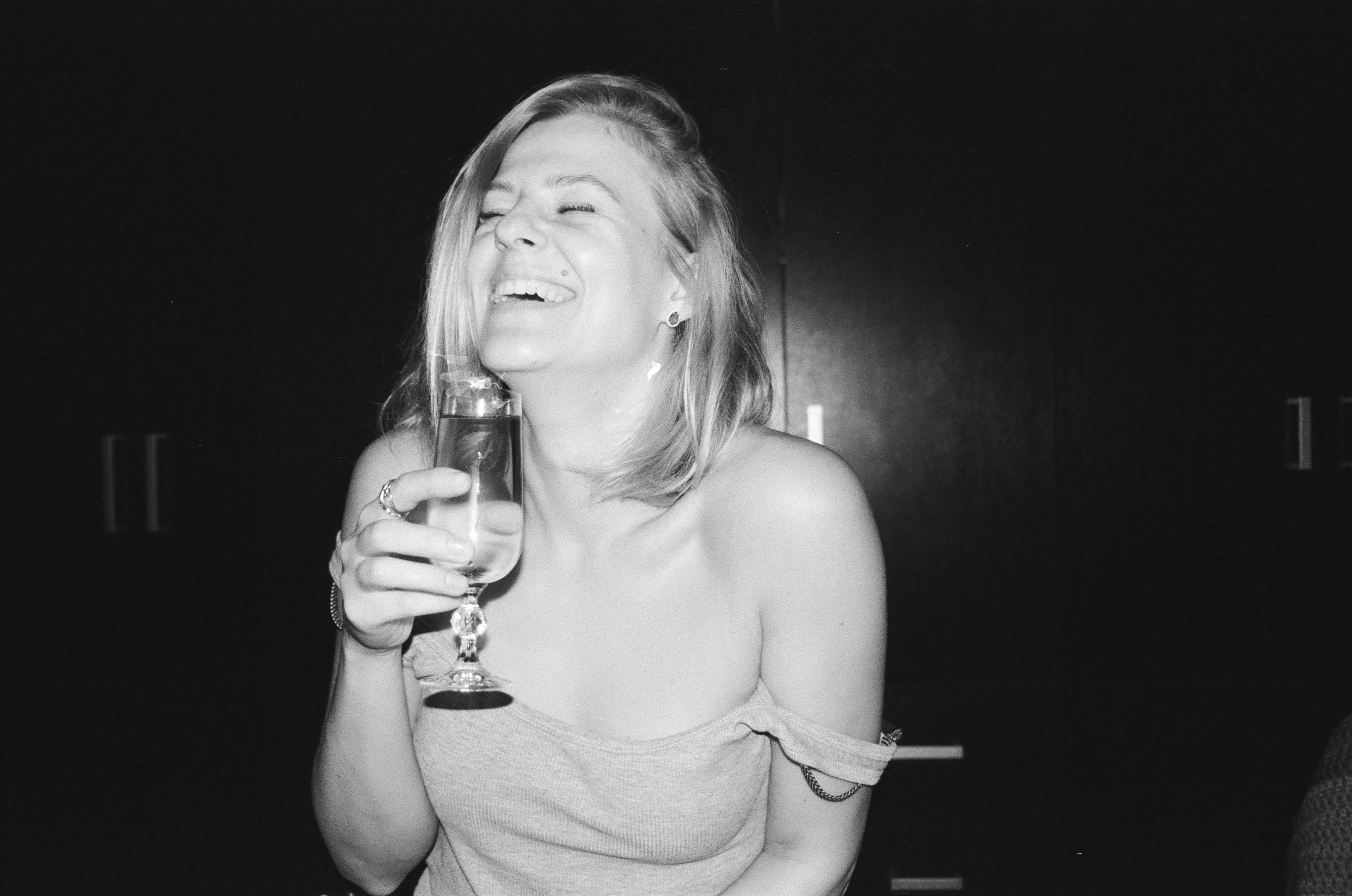 A woman laughing while holding a glass | Source: Pexels
