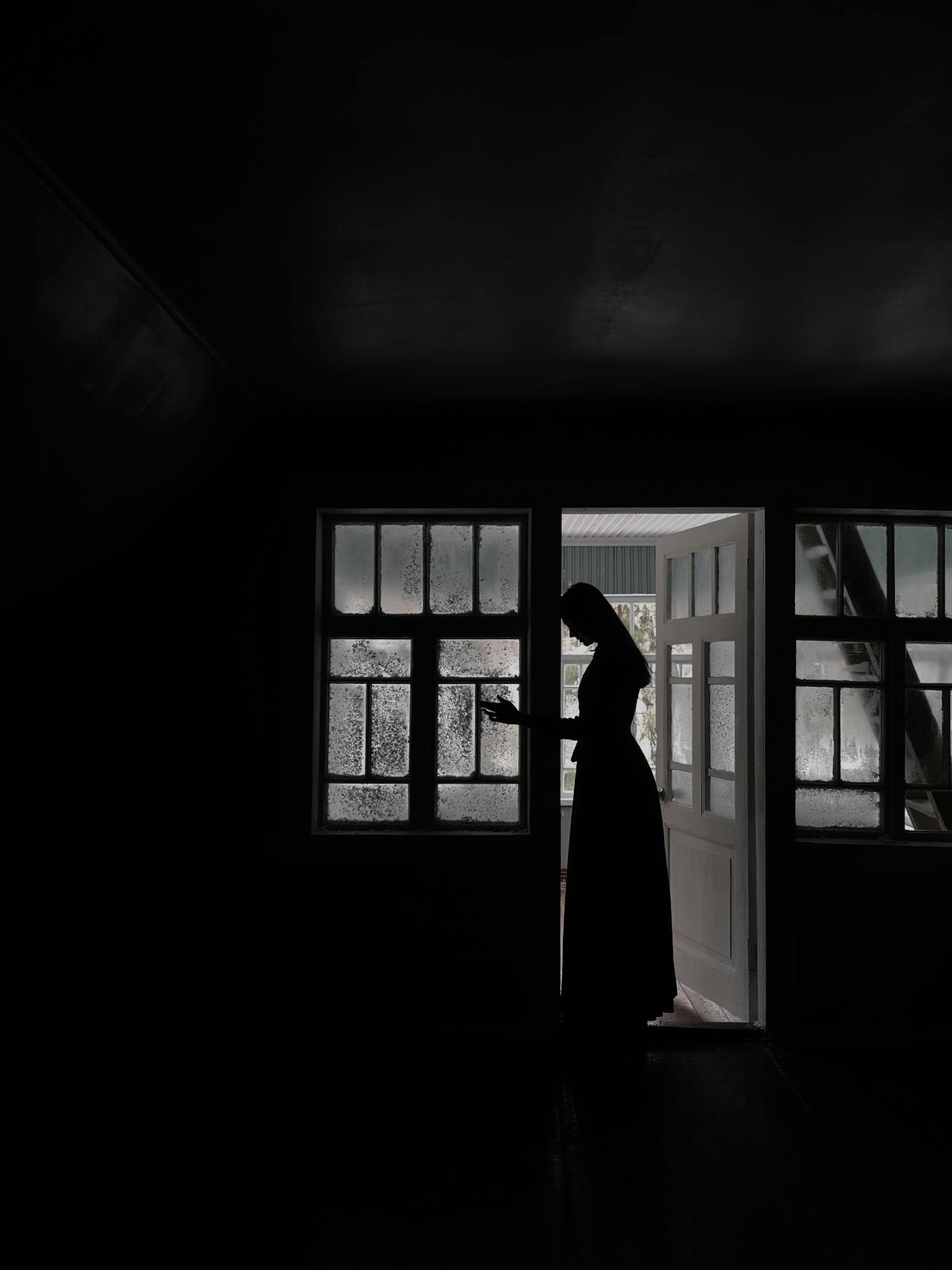 Silhouette of a woman standing in the doorway of her house | Source: Pexels