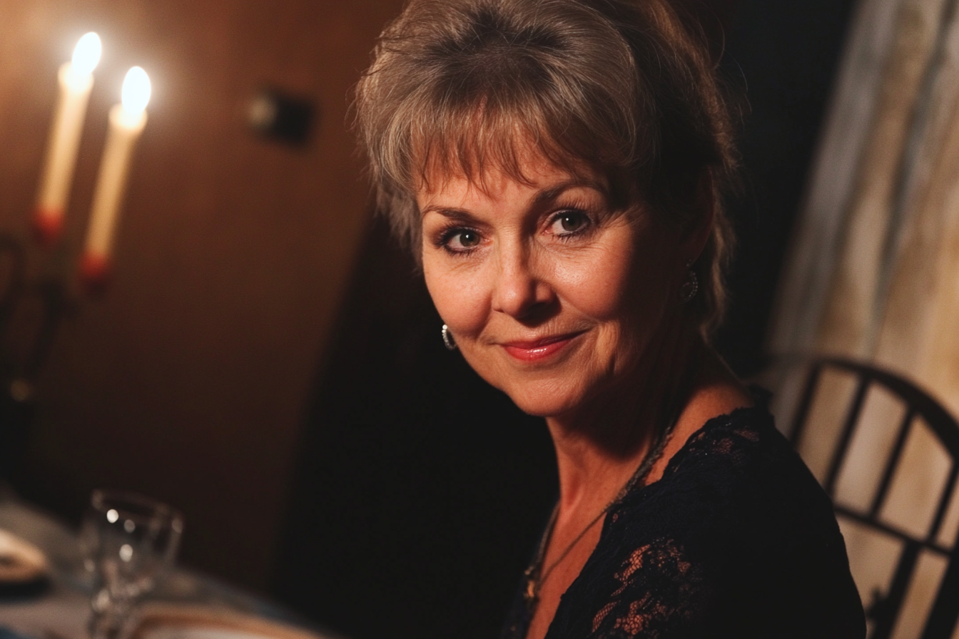 A woman at a dinner table smiling | Source: no source