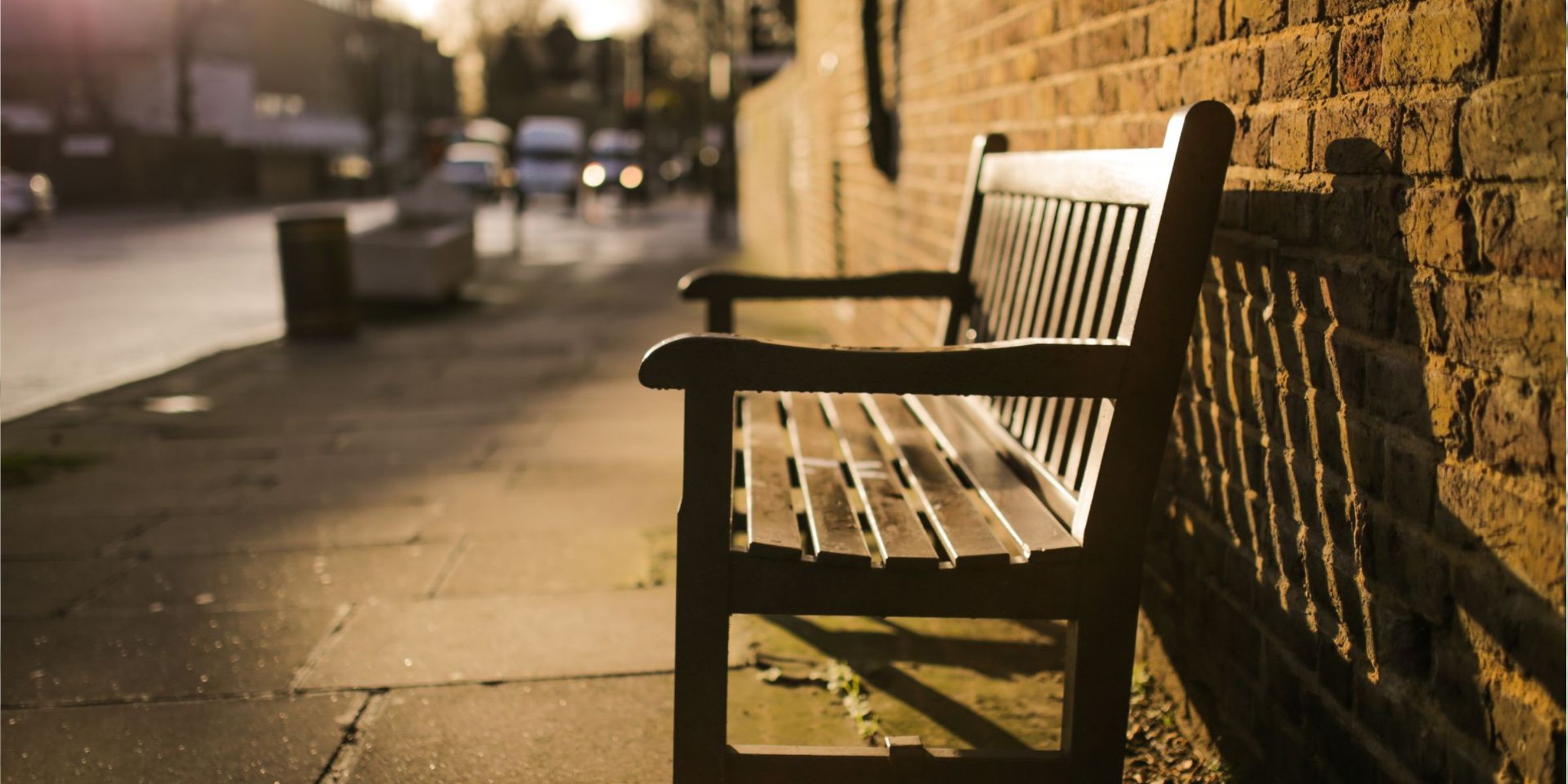 An empty bench along a quiet sidewalk in the warm glow of late afternoon light | Source: Pexels