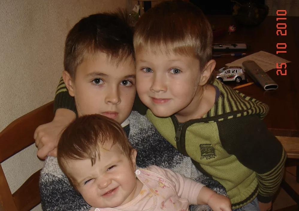 The kids are hugging while sitting in the kitchen | Source: Shutterstock.com