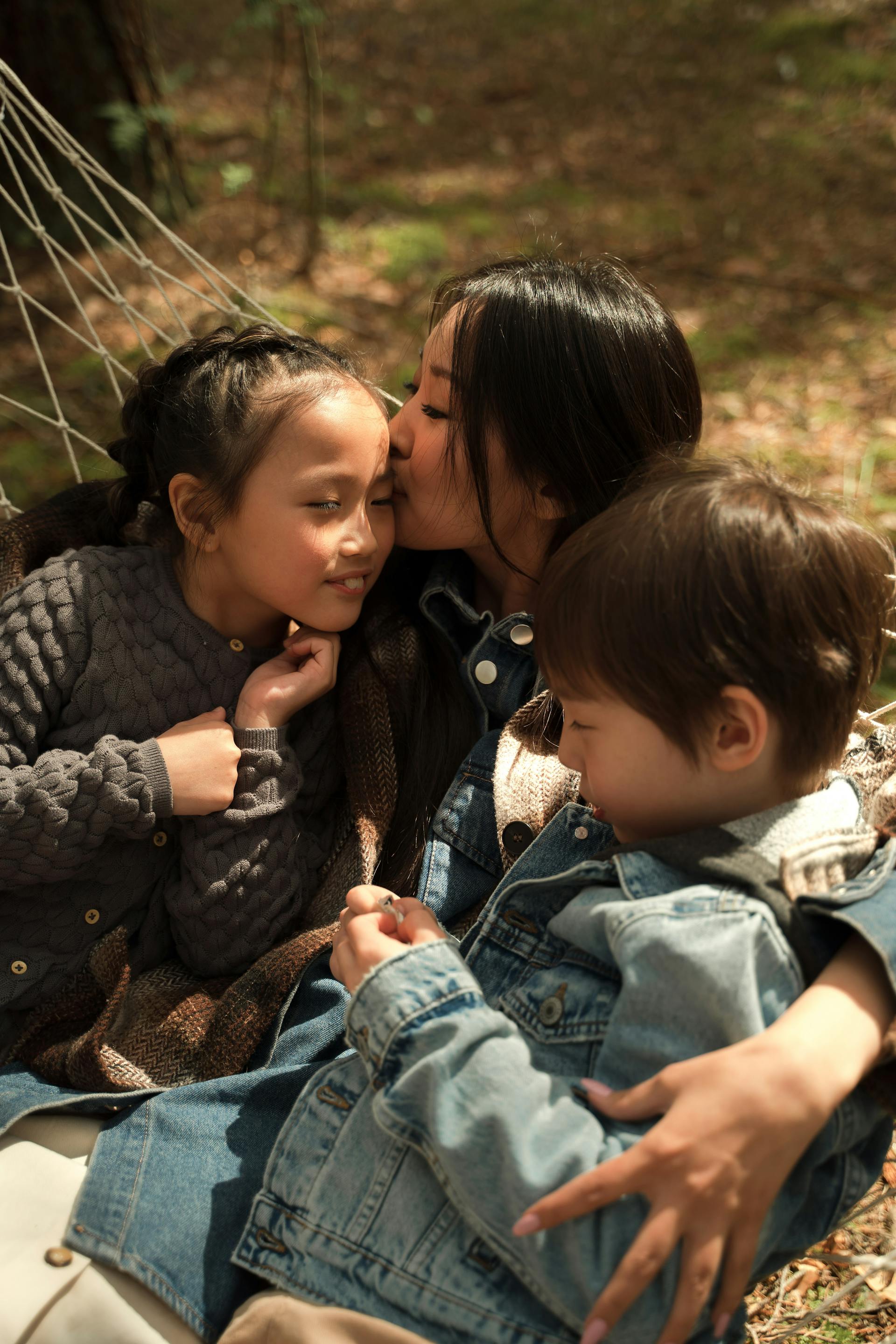 A woman kissing her children | Source: Pexels