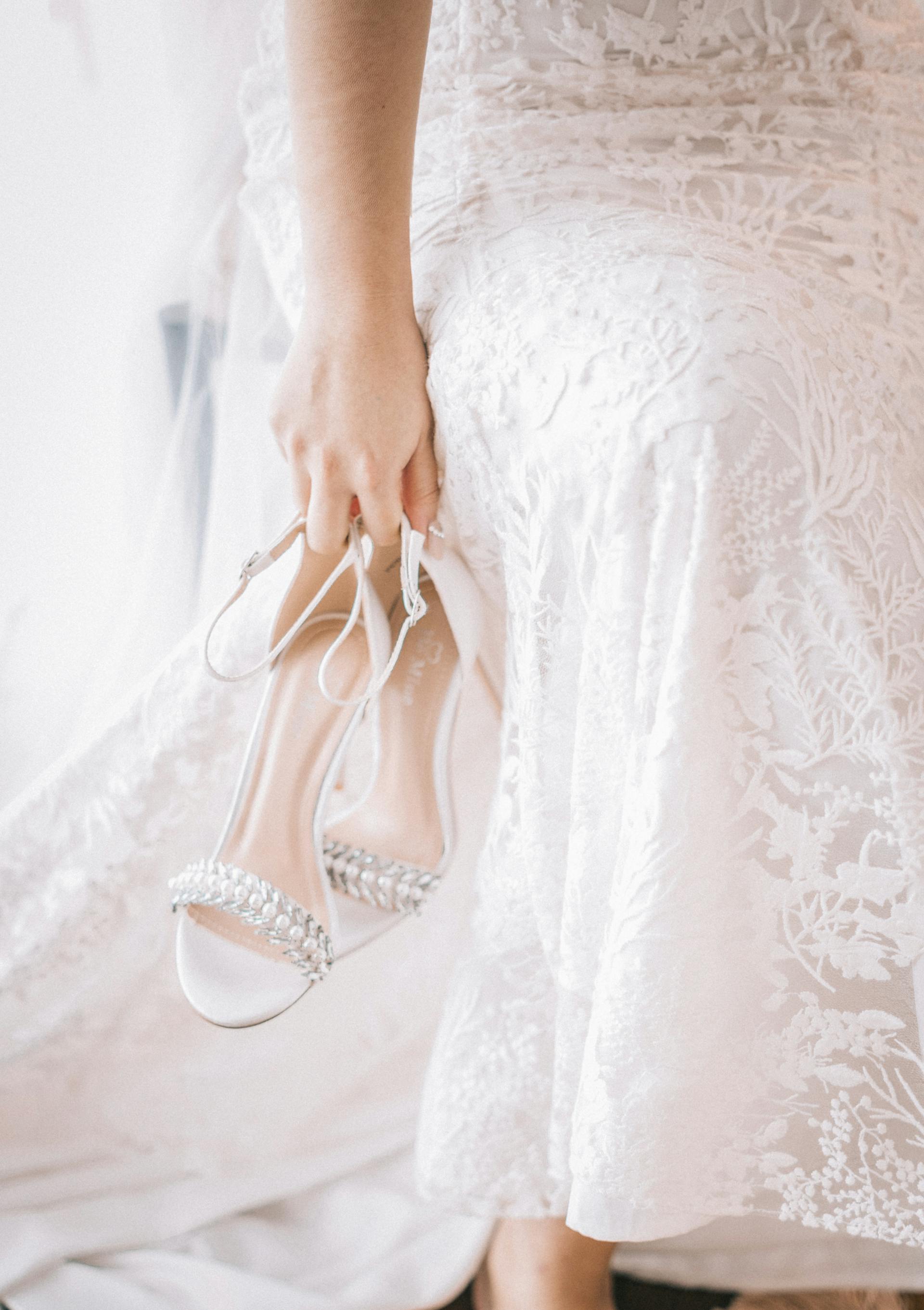 A woman in a white dress carrying her sandals | Source: Pexels