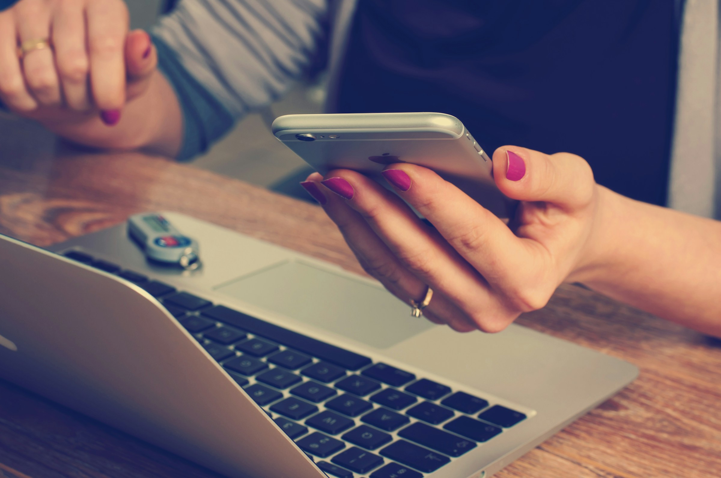 A woman using her phone while working on a computer | Source: Unsplash