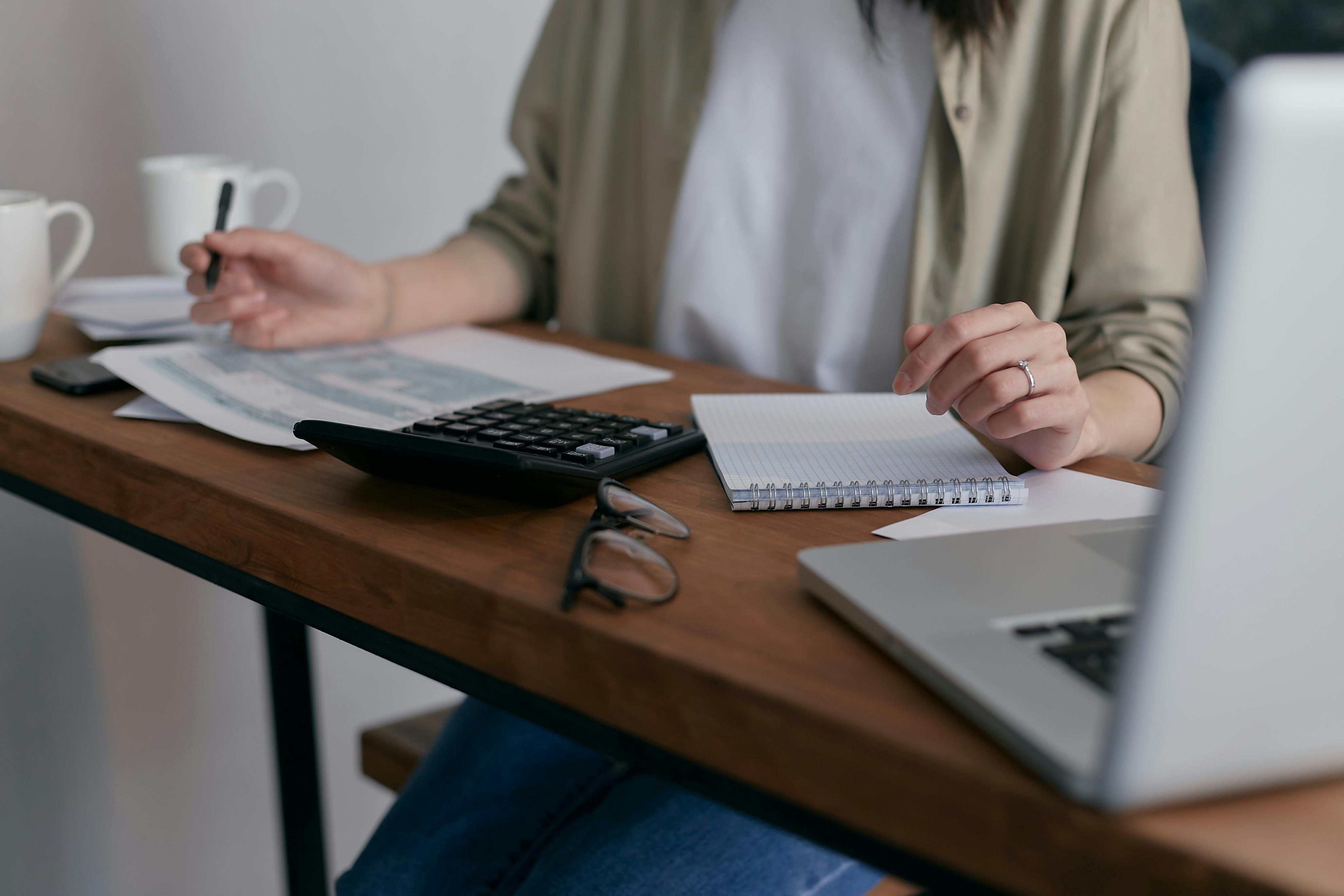 Woman taking notes and using a calculator | Source: Pexels