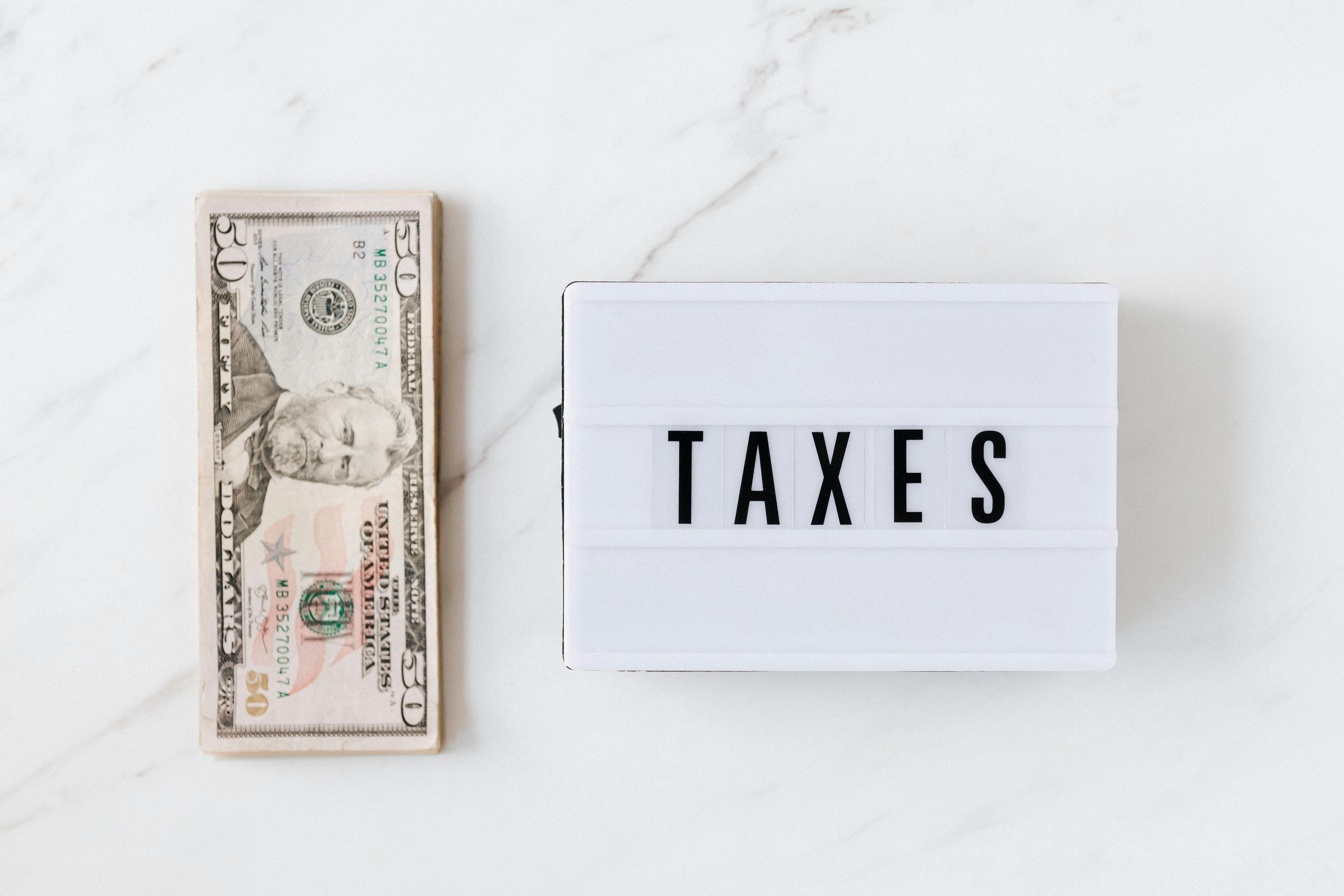 A stack of fifty-dollar bills is placed next to a lightbox | Source: Pexels