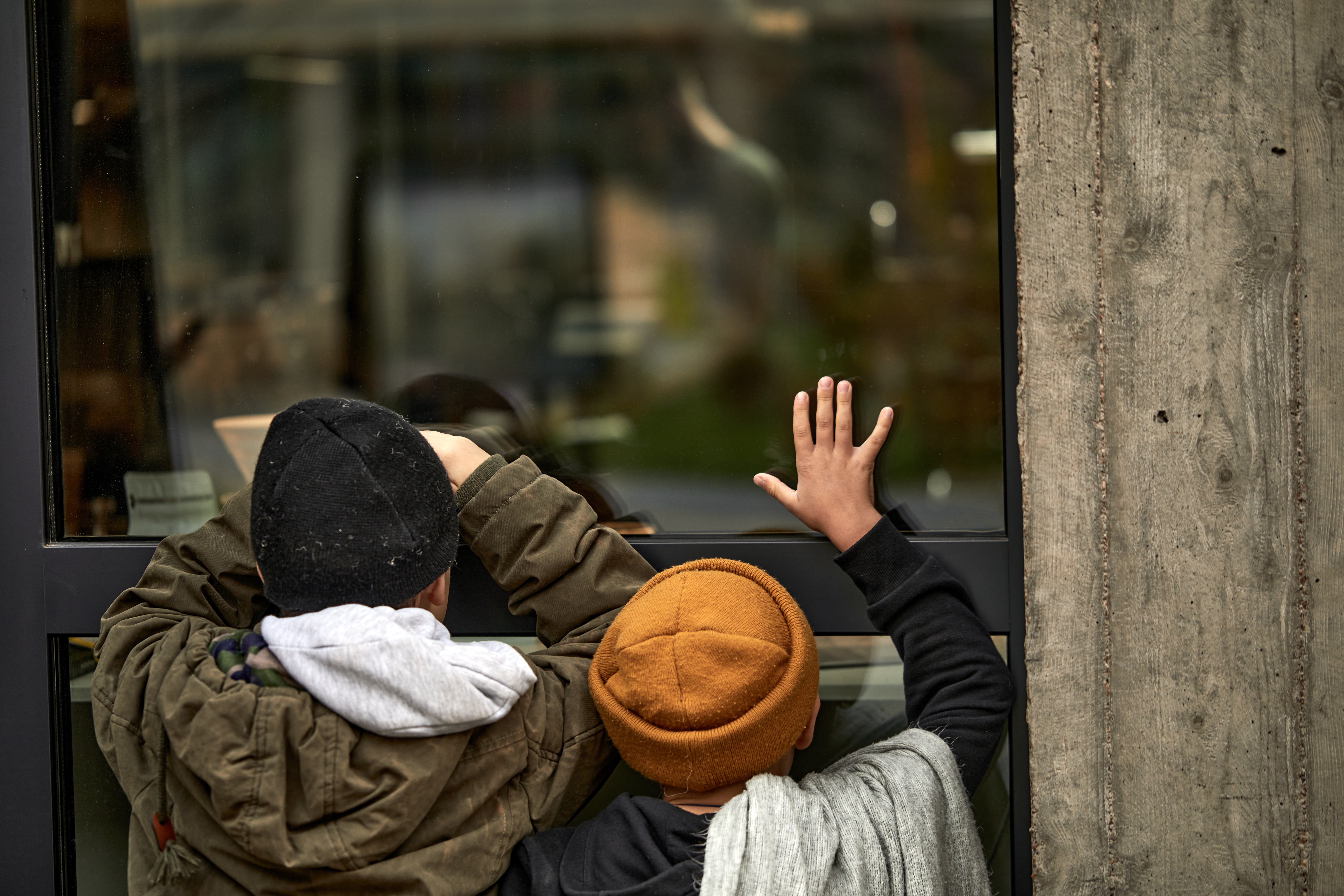 Two poor homeless children leaned on window of building | Source: Shutterstock.com