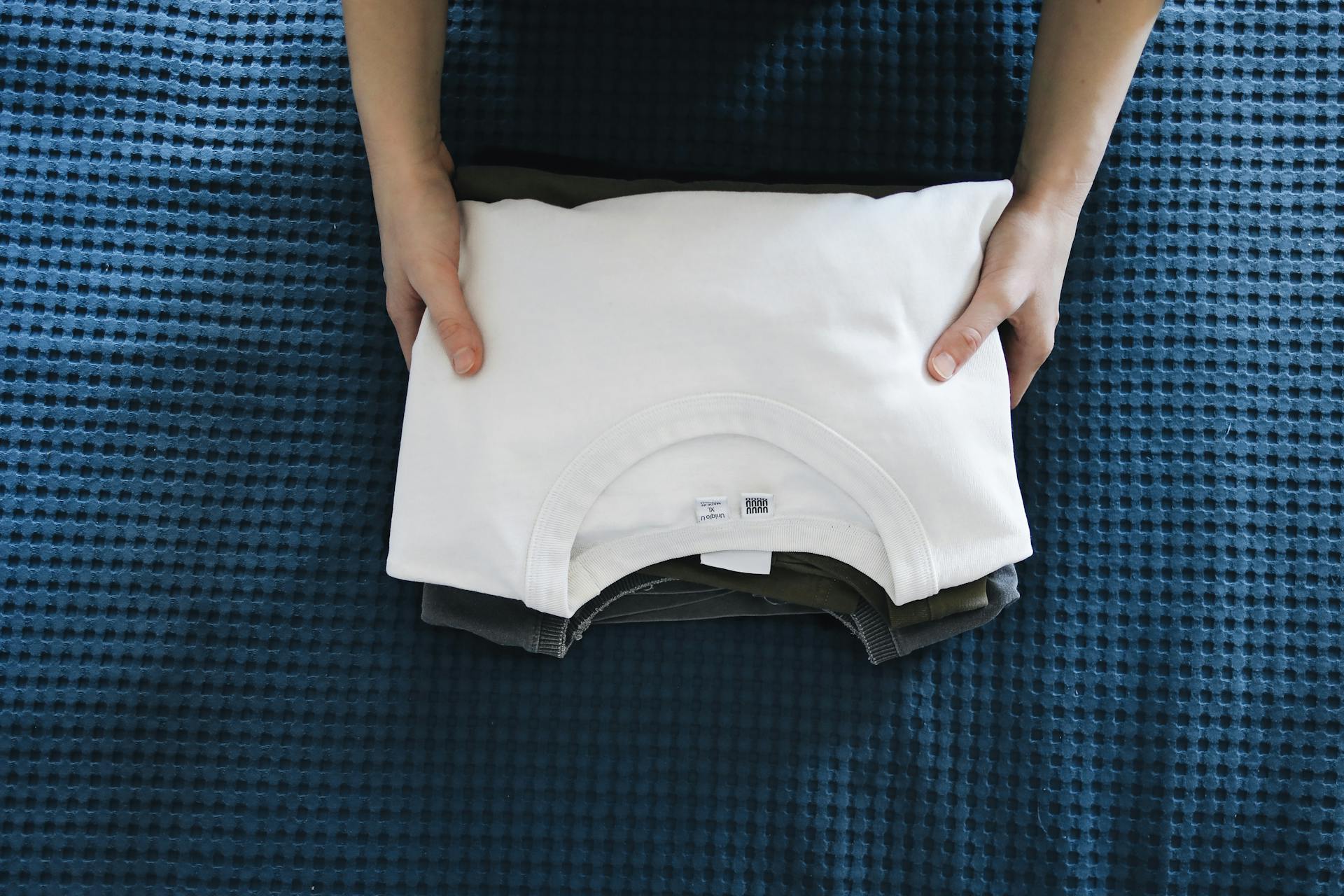 A woman holding a stack of folded T-shirts | Source: Pexels