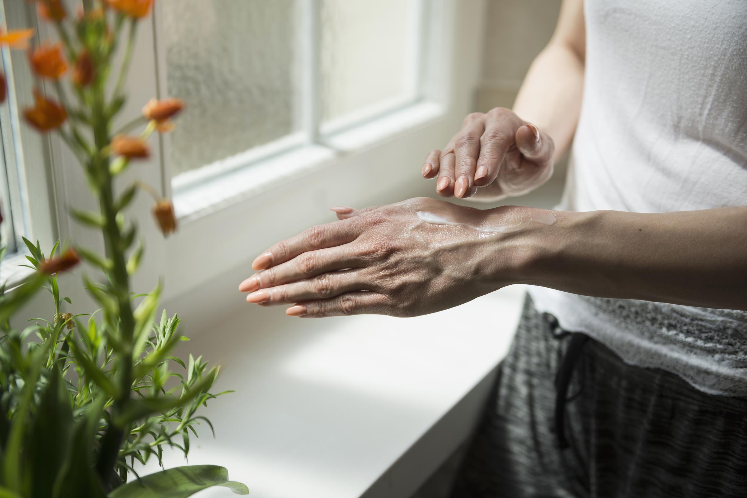 A woman applying sunscreen inside her home | Source: Getty Images