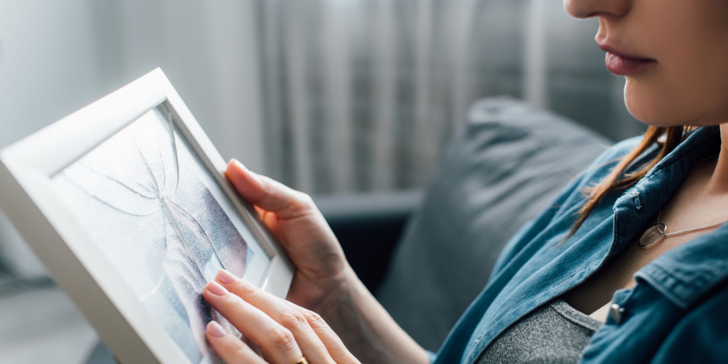 A woman holding a framed photograph while reflecting on a memory | Source: Shutterstock