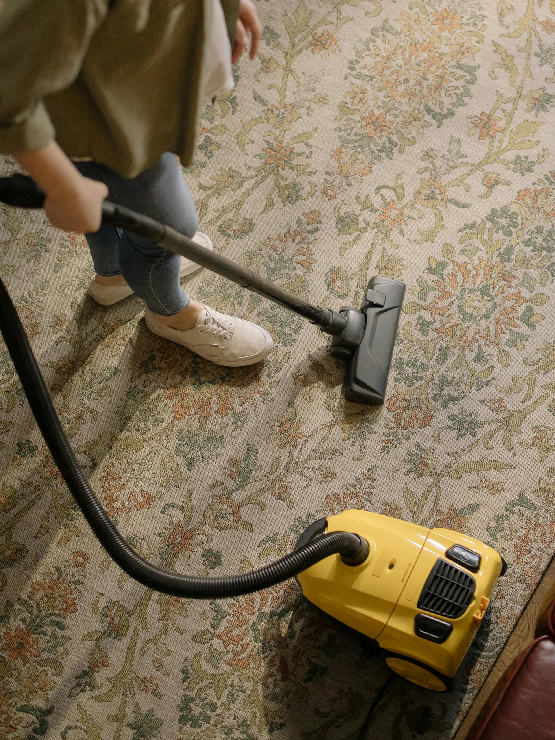 A woman vacuuming a carpet | Source: Pexels
