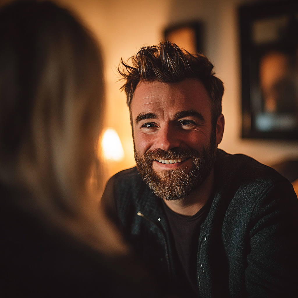 A smiling man talking to a woman in her living room | Source: no source