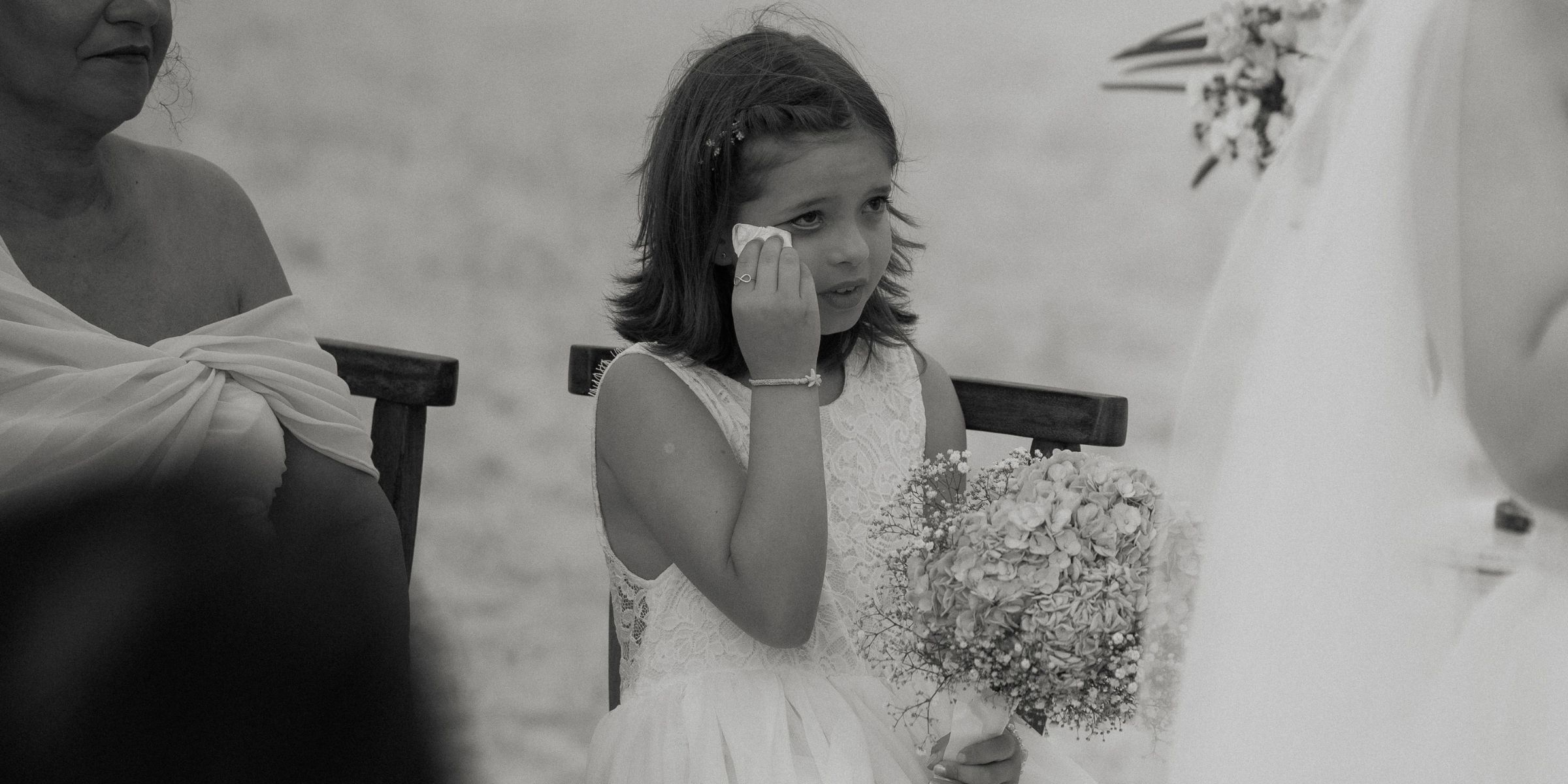 A flower girl wiping away her tears at a wedding | Source: Pexels