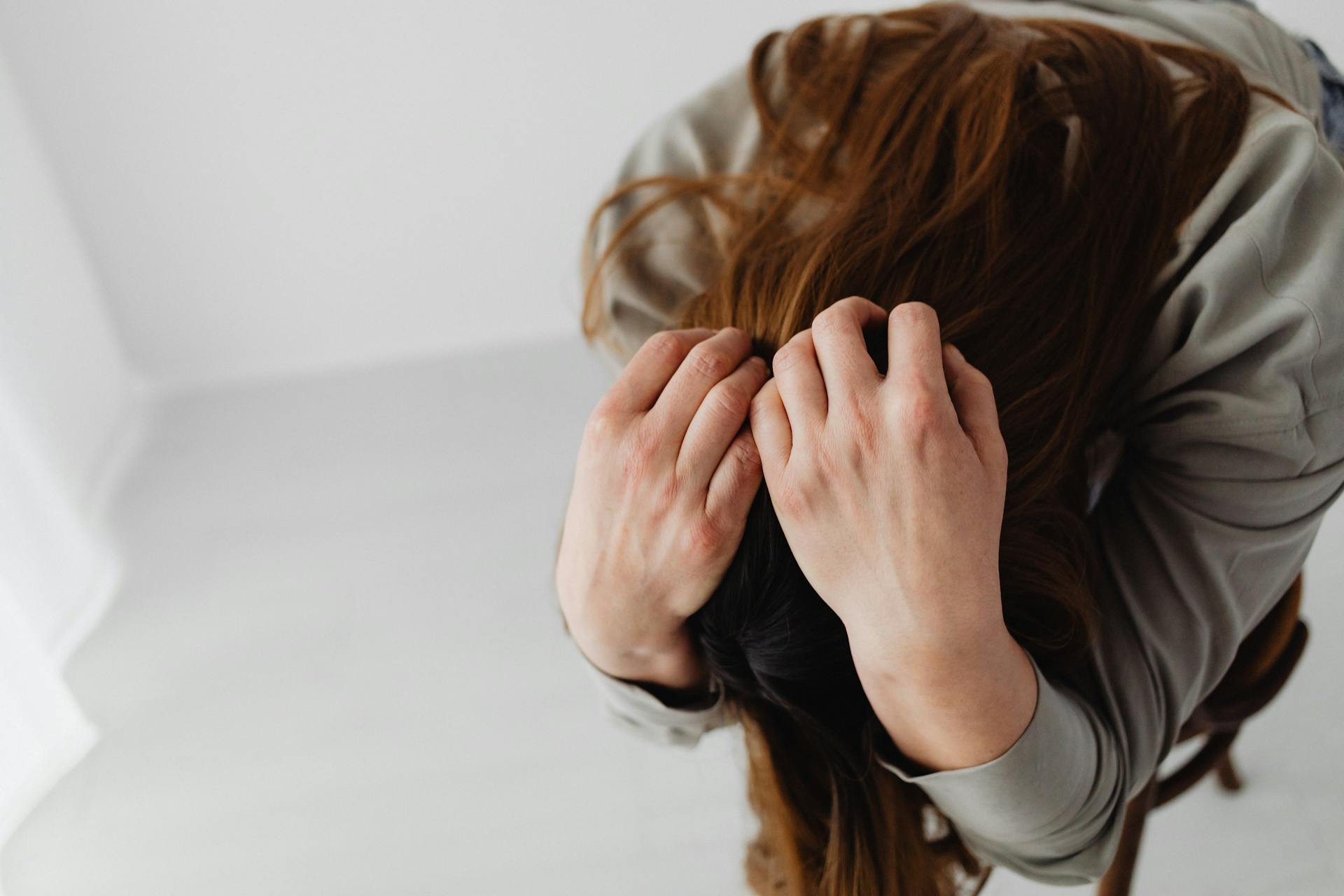 A woman sitting with her head in her hands | Source: Pexels