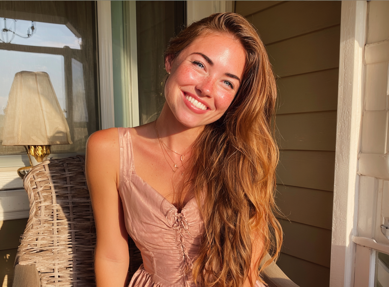 A smiling young woman wearing a pink dress | Source: No source