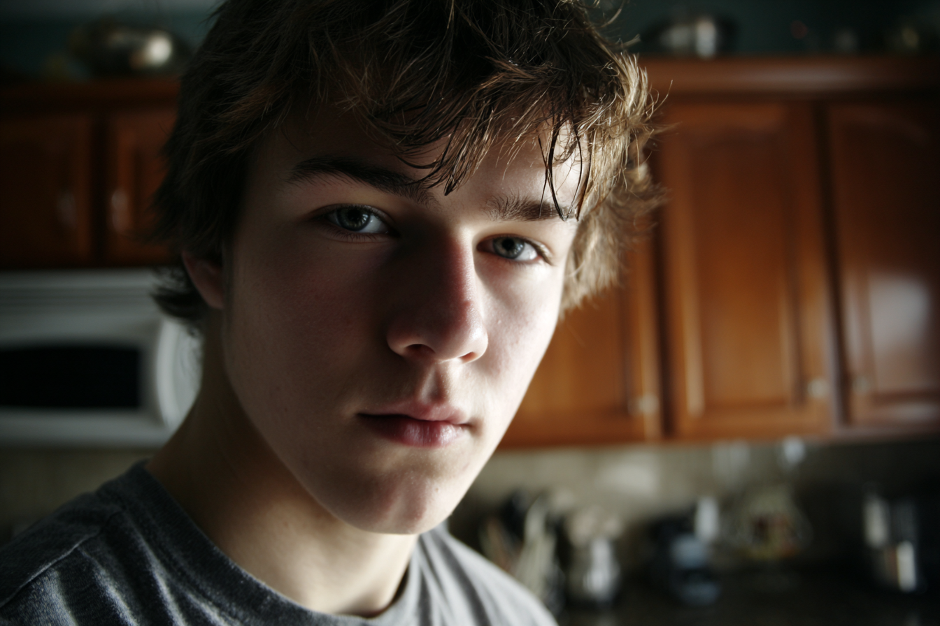 A teenage boy standing in the kitchen and looking at someone | Source: No source