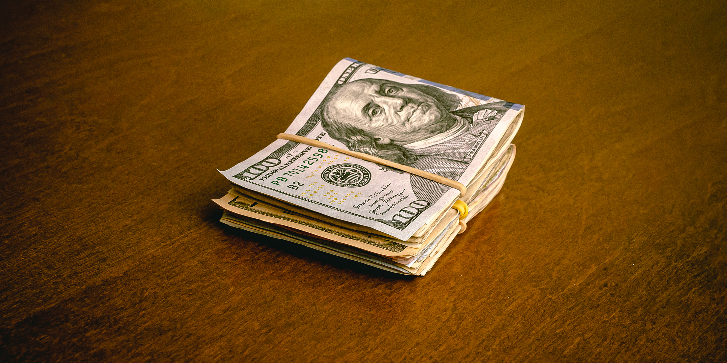 A folded stack of dollar bills on a table | Source: Shutterstock