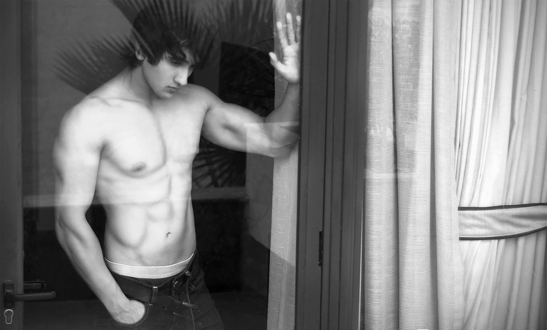 A shirtless man standing near a window | Source: Pexels