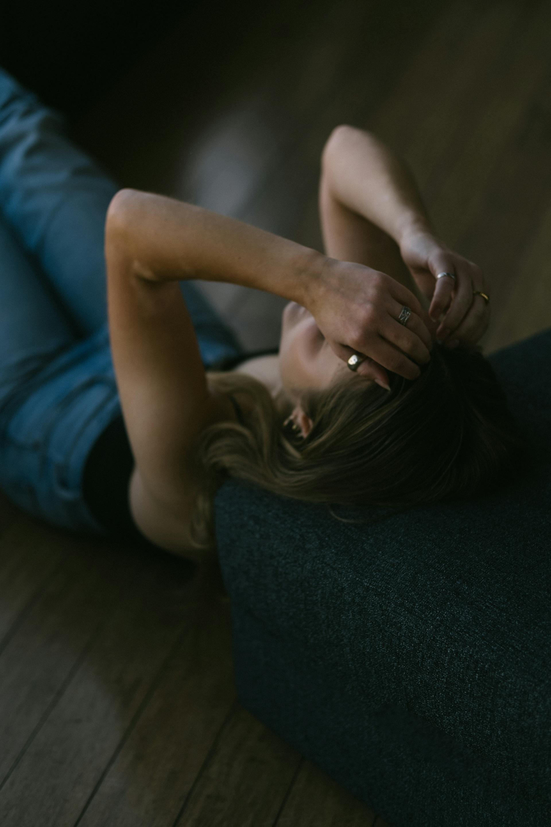 A woman lying down on the floor with her hands on her head | Source: Pexels