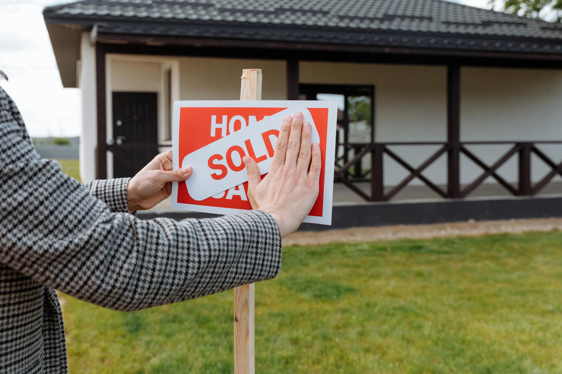 A person putting a sticker on top of a sign outside a house | Source: Pexels