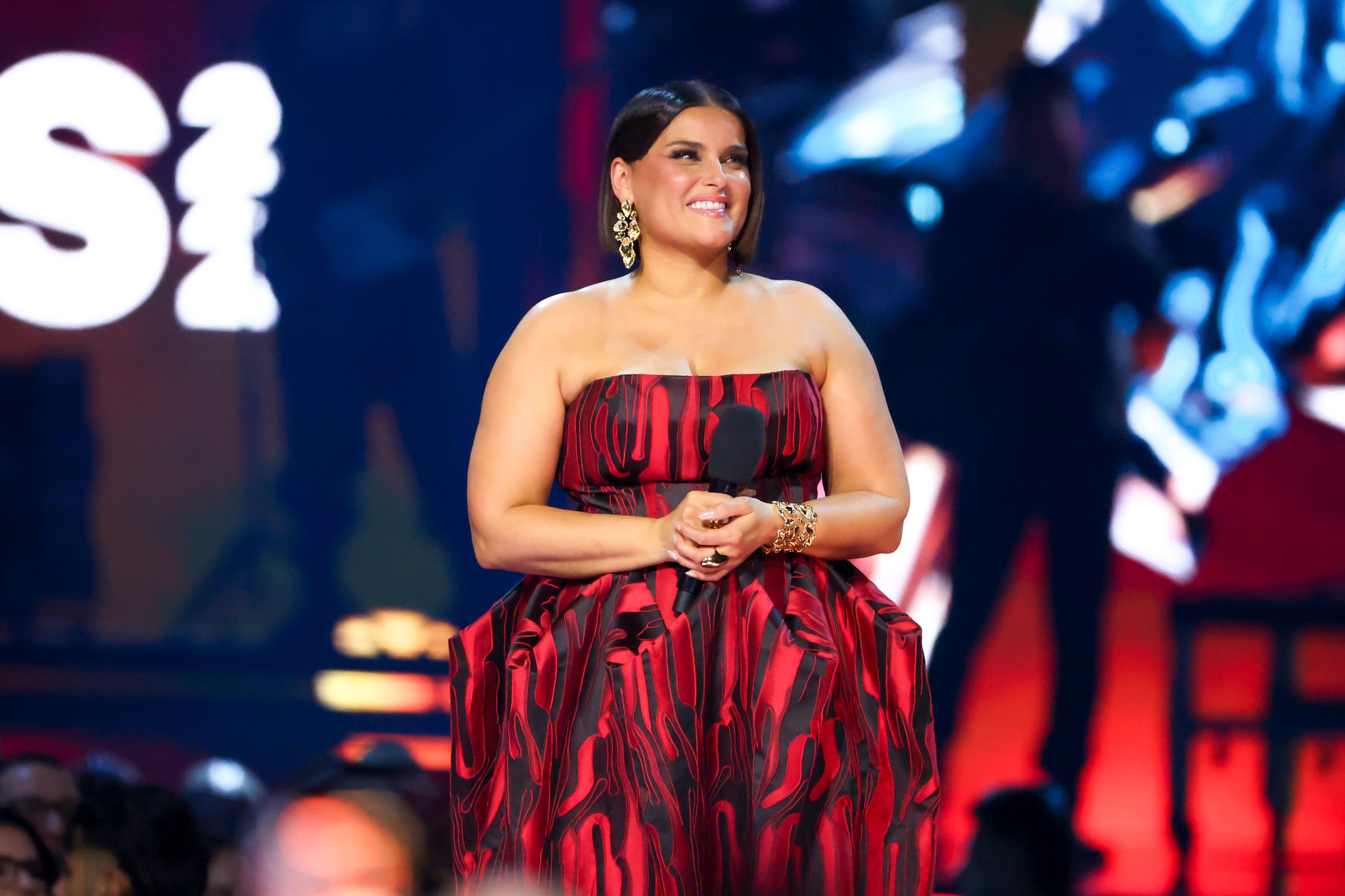 Nelly Furtado stands onstage at the JUNO Awards in Hamilton, Ontario, smiling as she holds a microphone during her Canadian Music Hall of Fame induction moment.