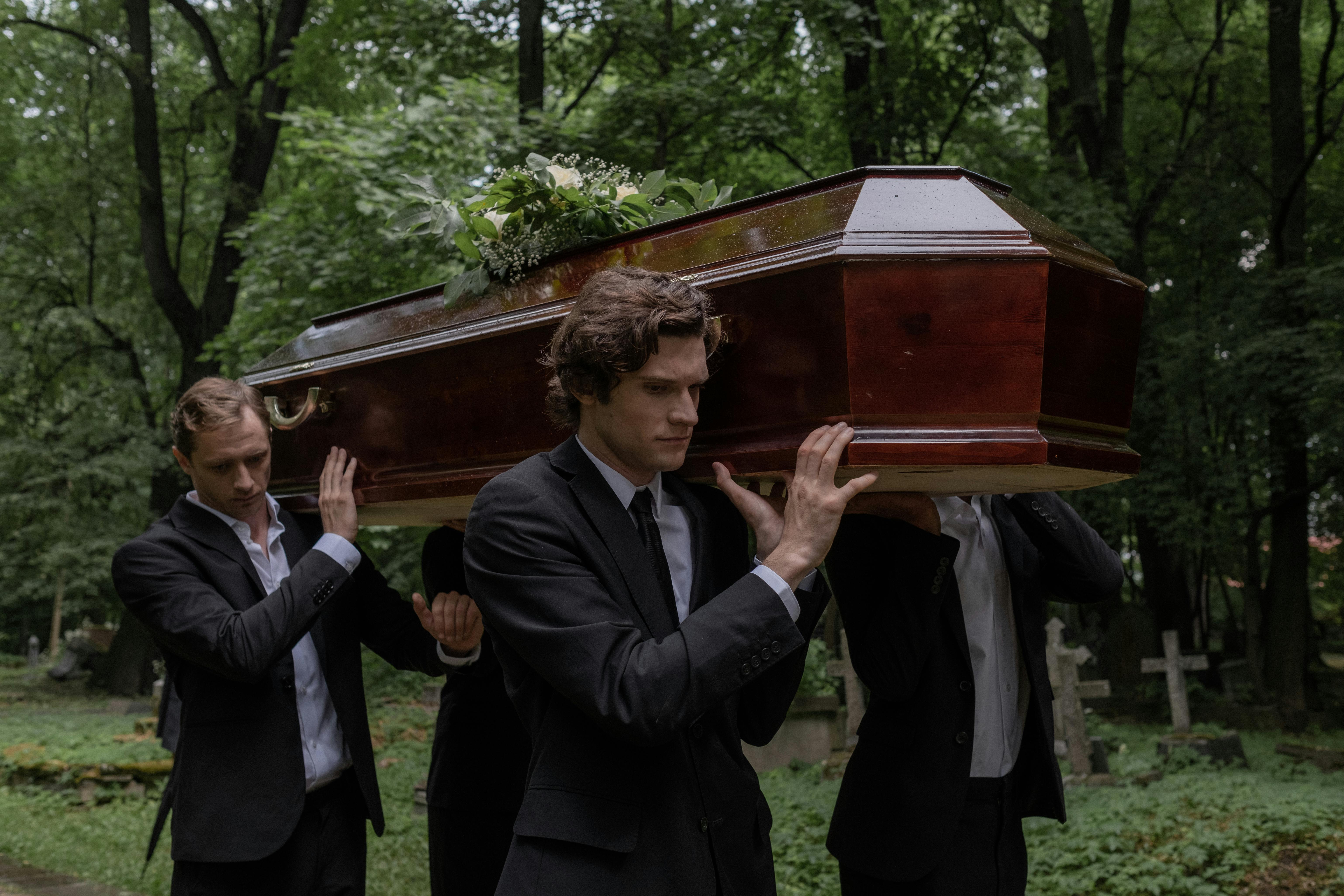 Men carrying a coffin in a graveyard | Source: no source