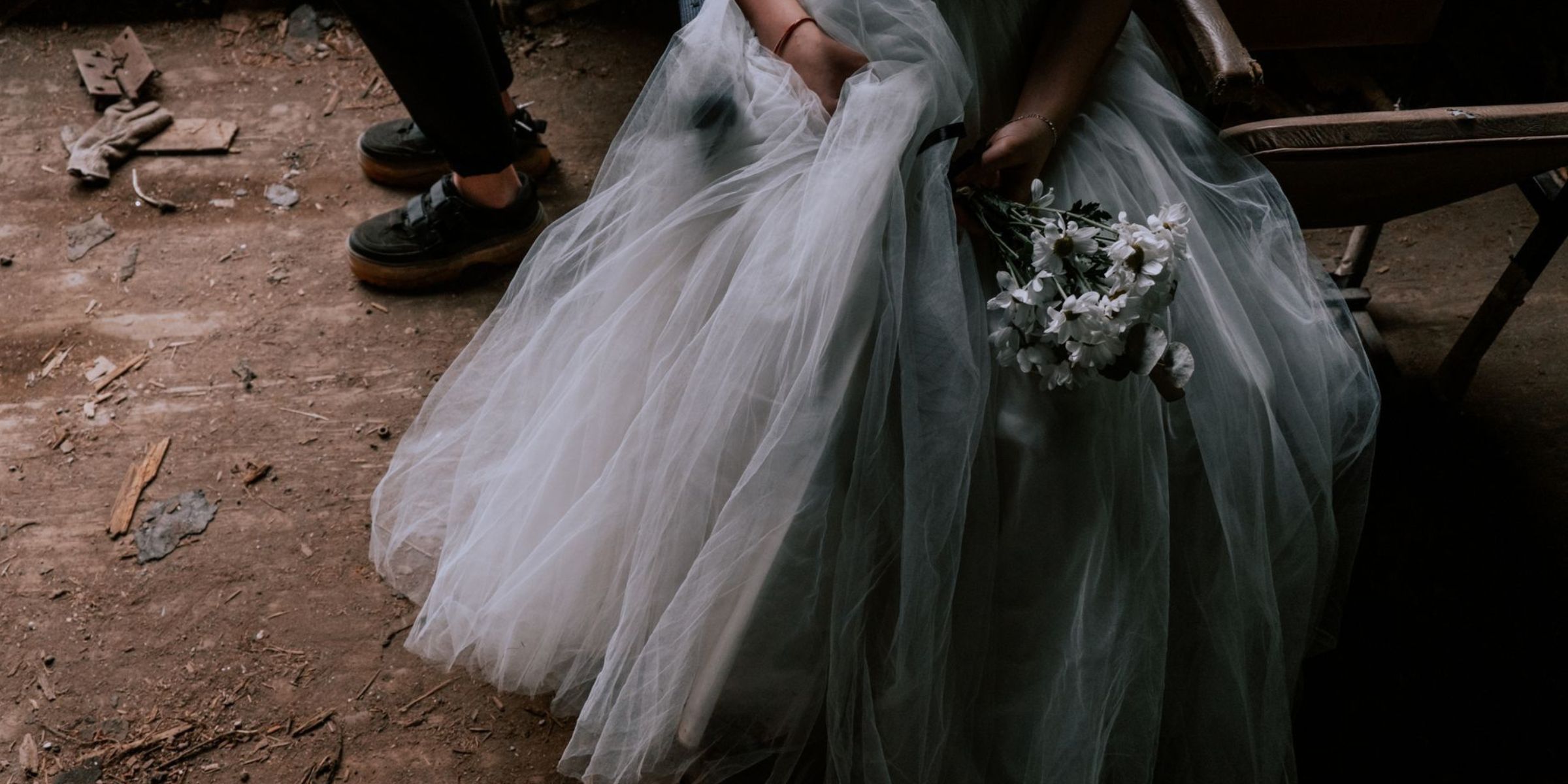 A bride in a flowing wedding gown holding a bouquet while seated in a rustic setting | Source: Pexels