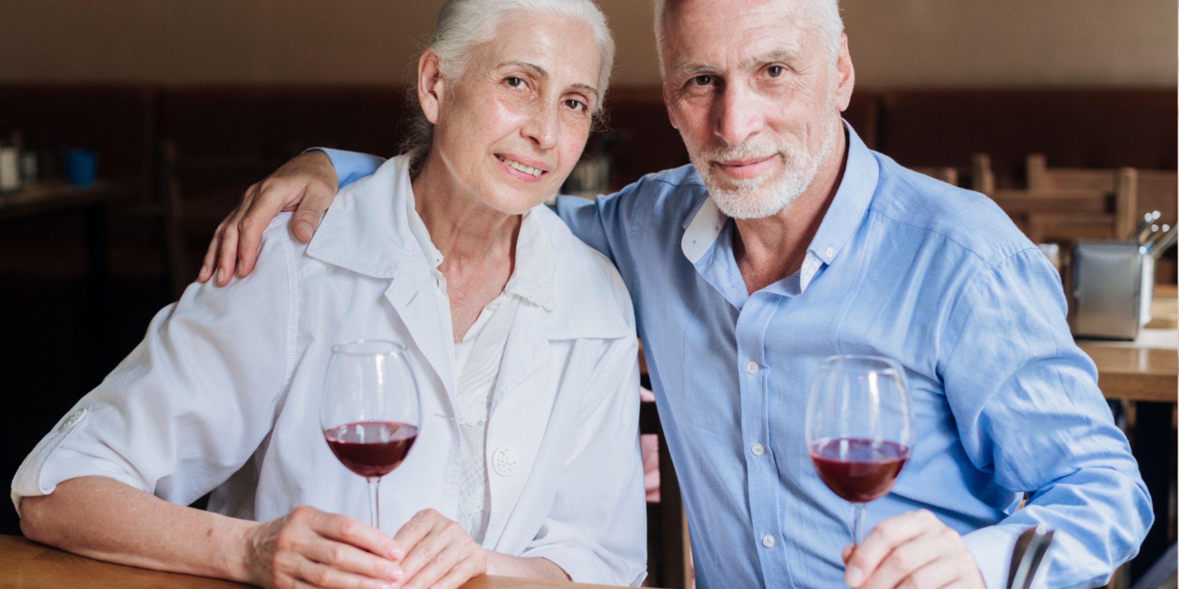 A senior couple sitting together at a restaurant table, sharing a quiet moment over glasses of wine | Source: No source