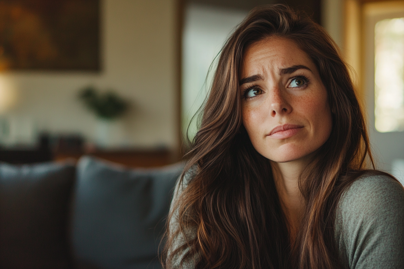 A thoughtful woman in a living room | Source: No source