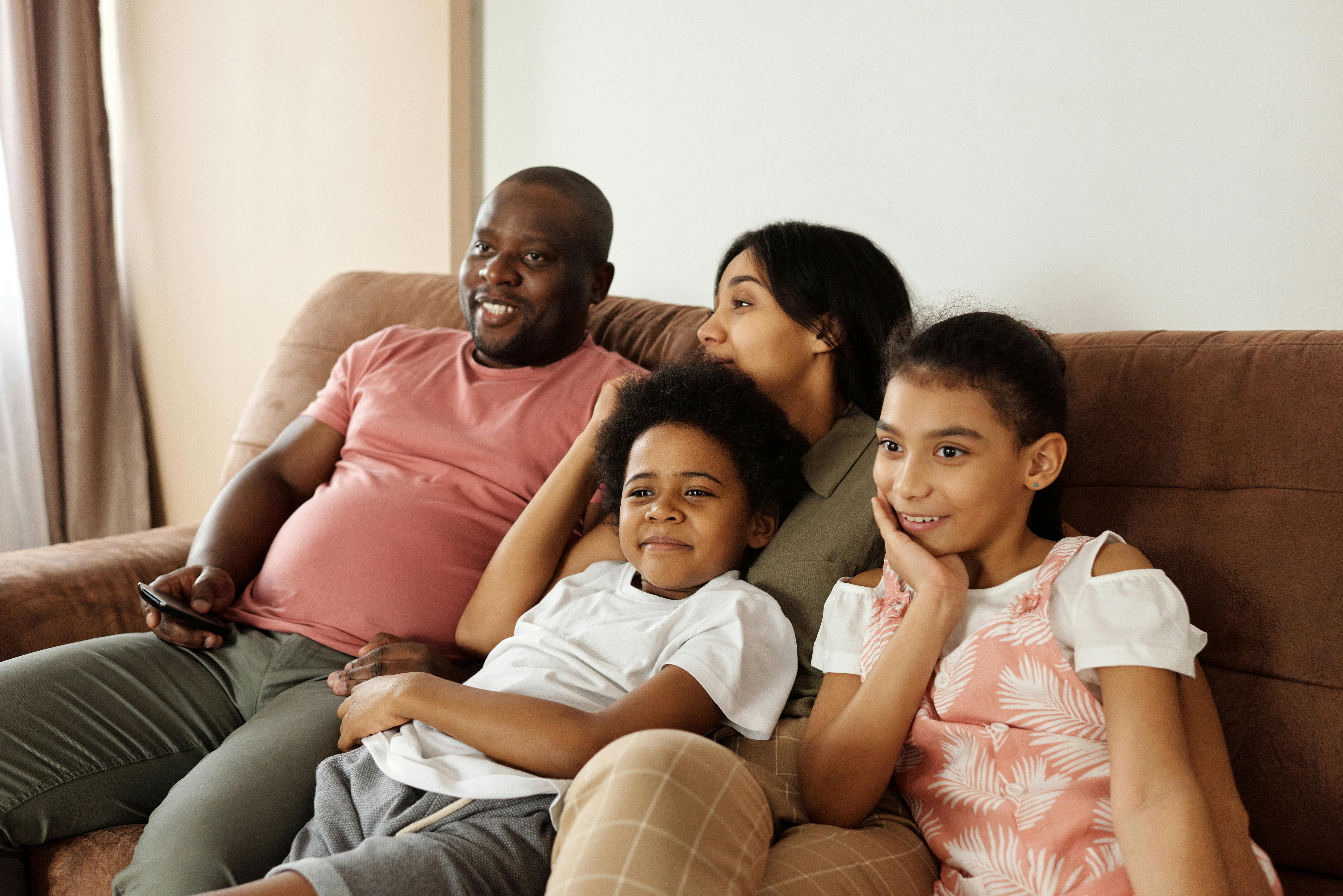 Happy family sitting on the couch watching TV | Source: Pexels