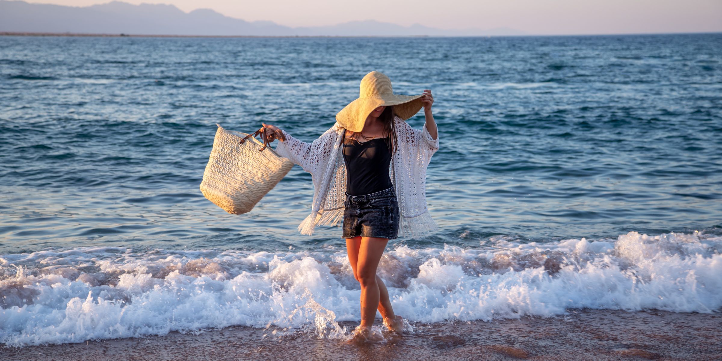 A happy woman enjoying the water at the beach | Source: No source