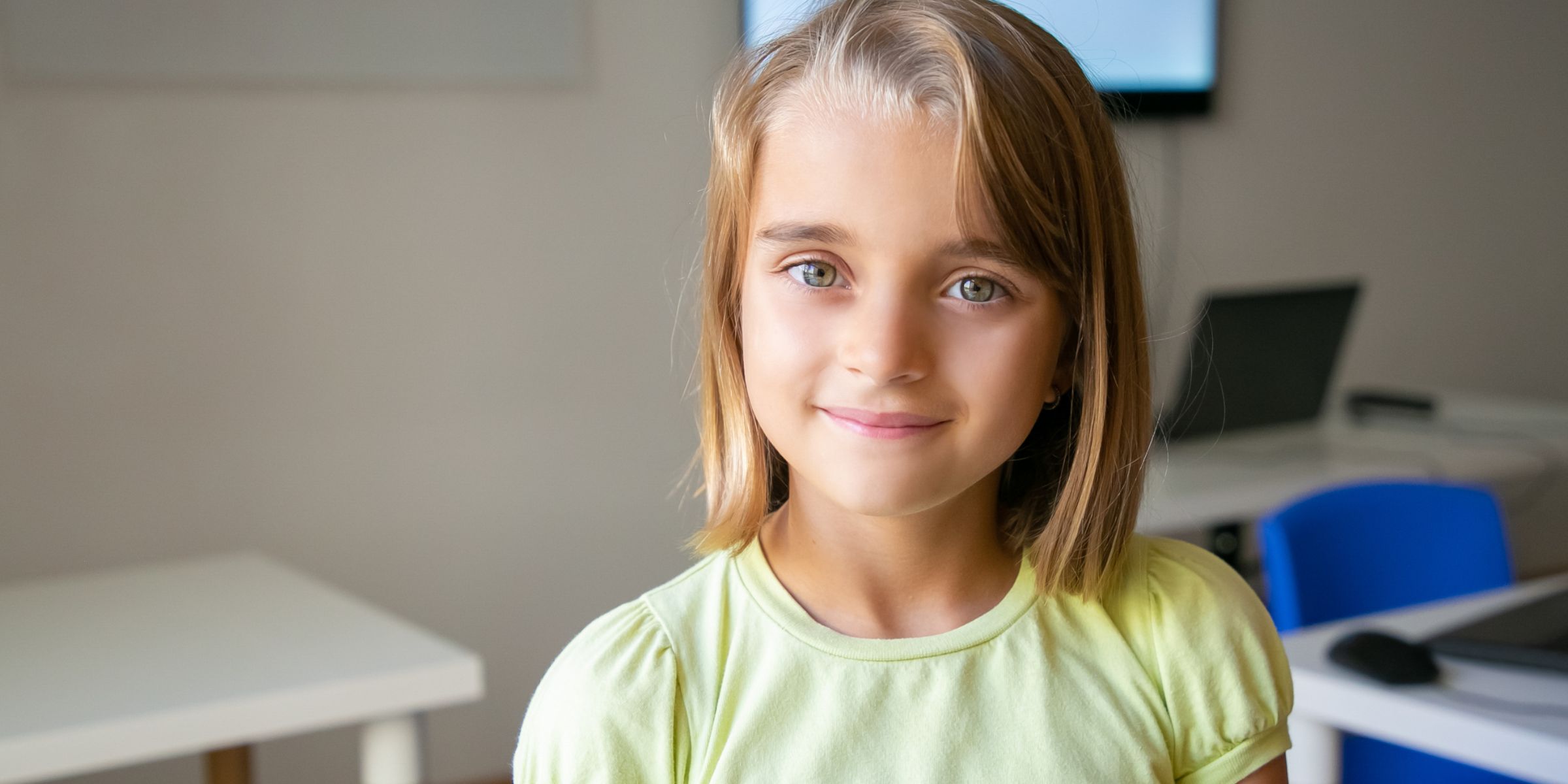 A smiling little girl in a yellow T-shirt | Source: No source