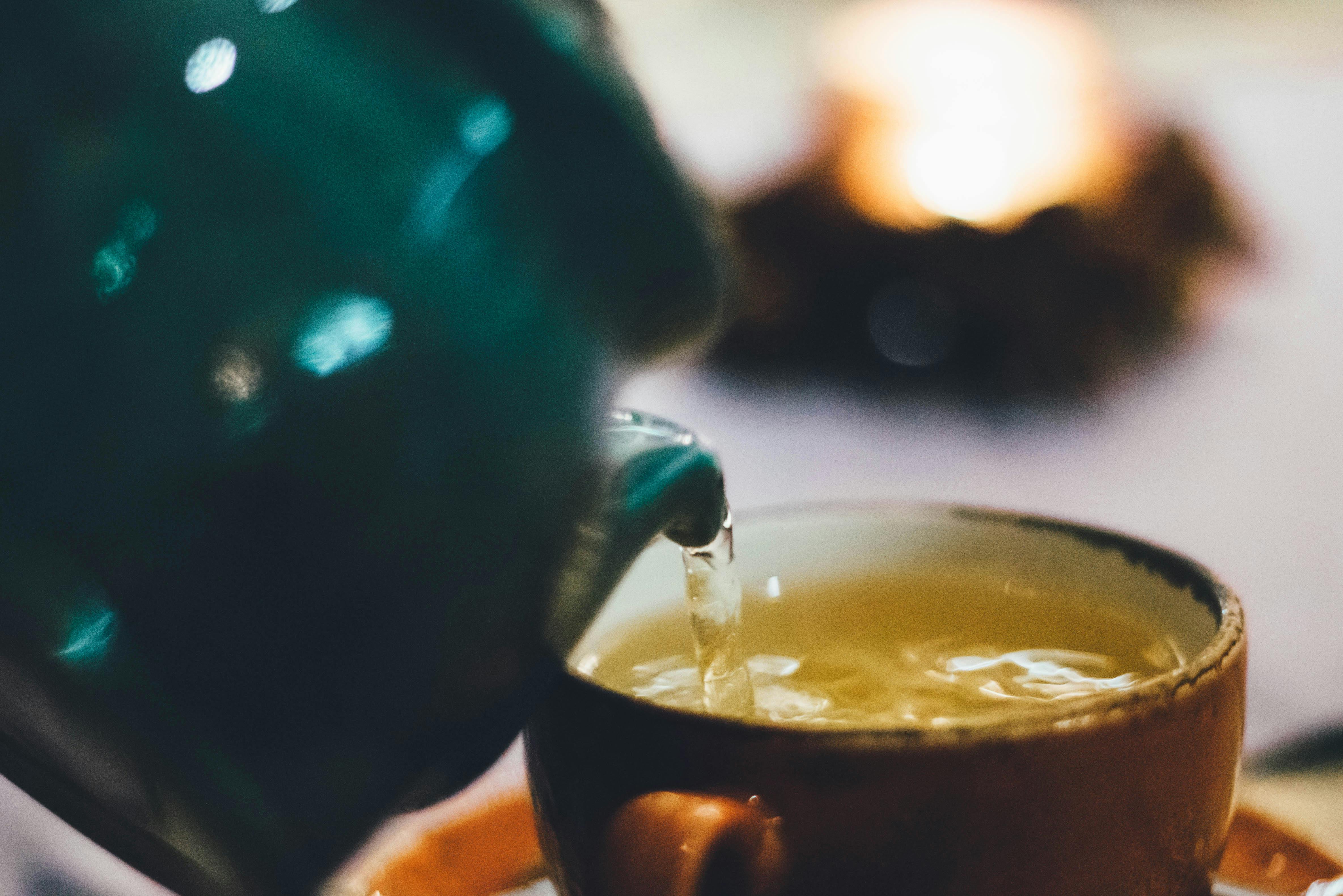 A man pours liquid into a brown ceramic cup | Source: Pexels