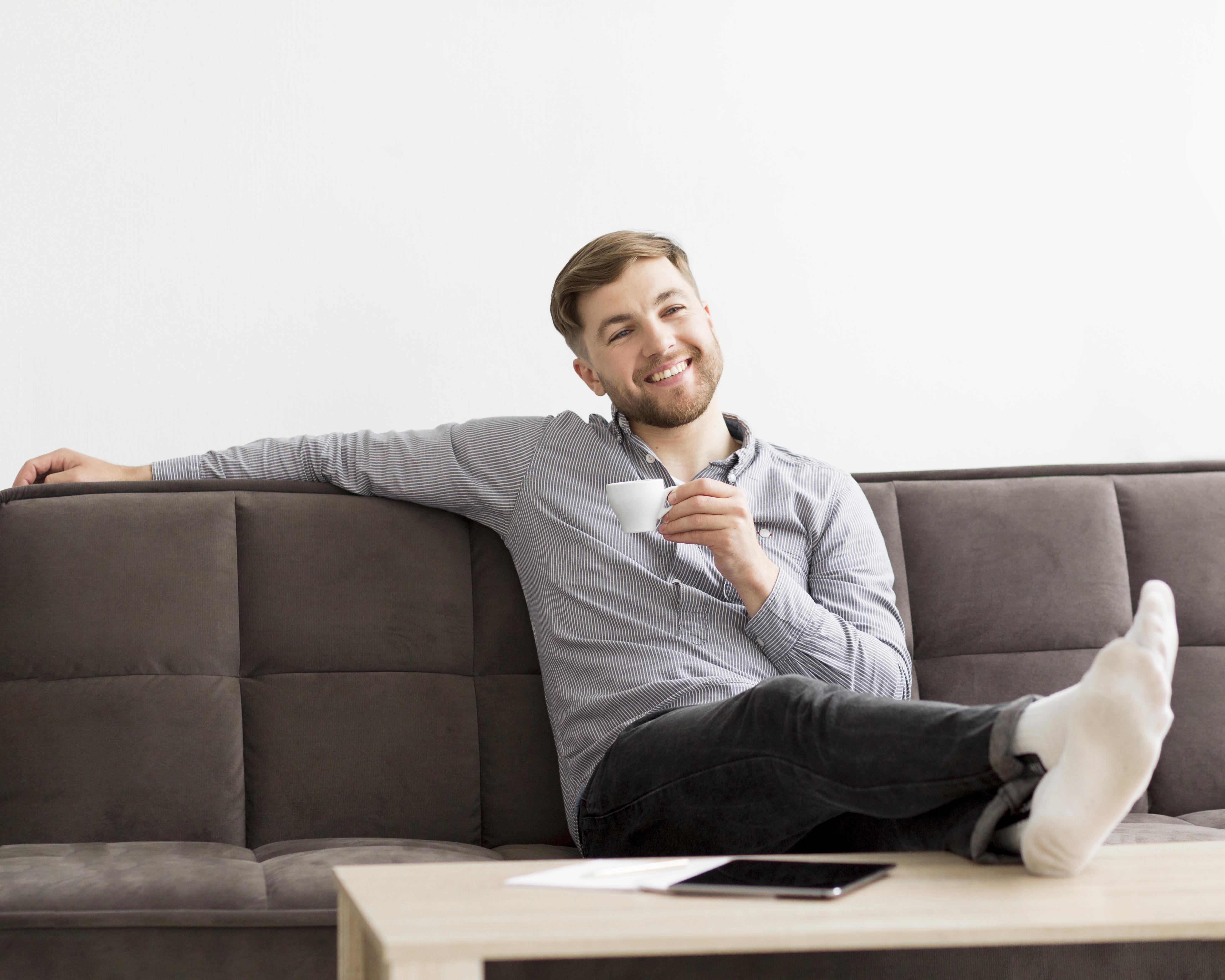 A smiling man on a couch | Source: Freepik