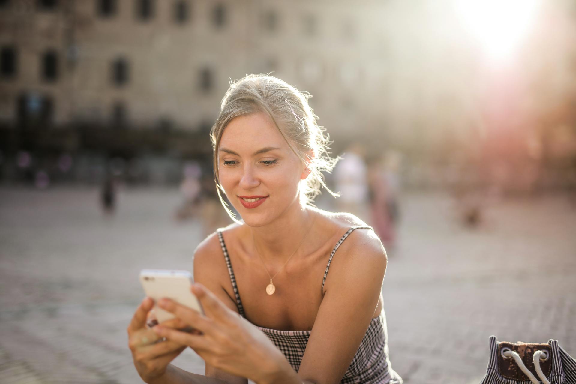 A woman smiling at her phone | Source: Pexels