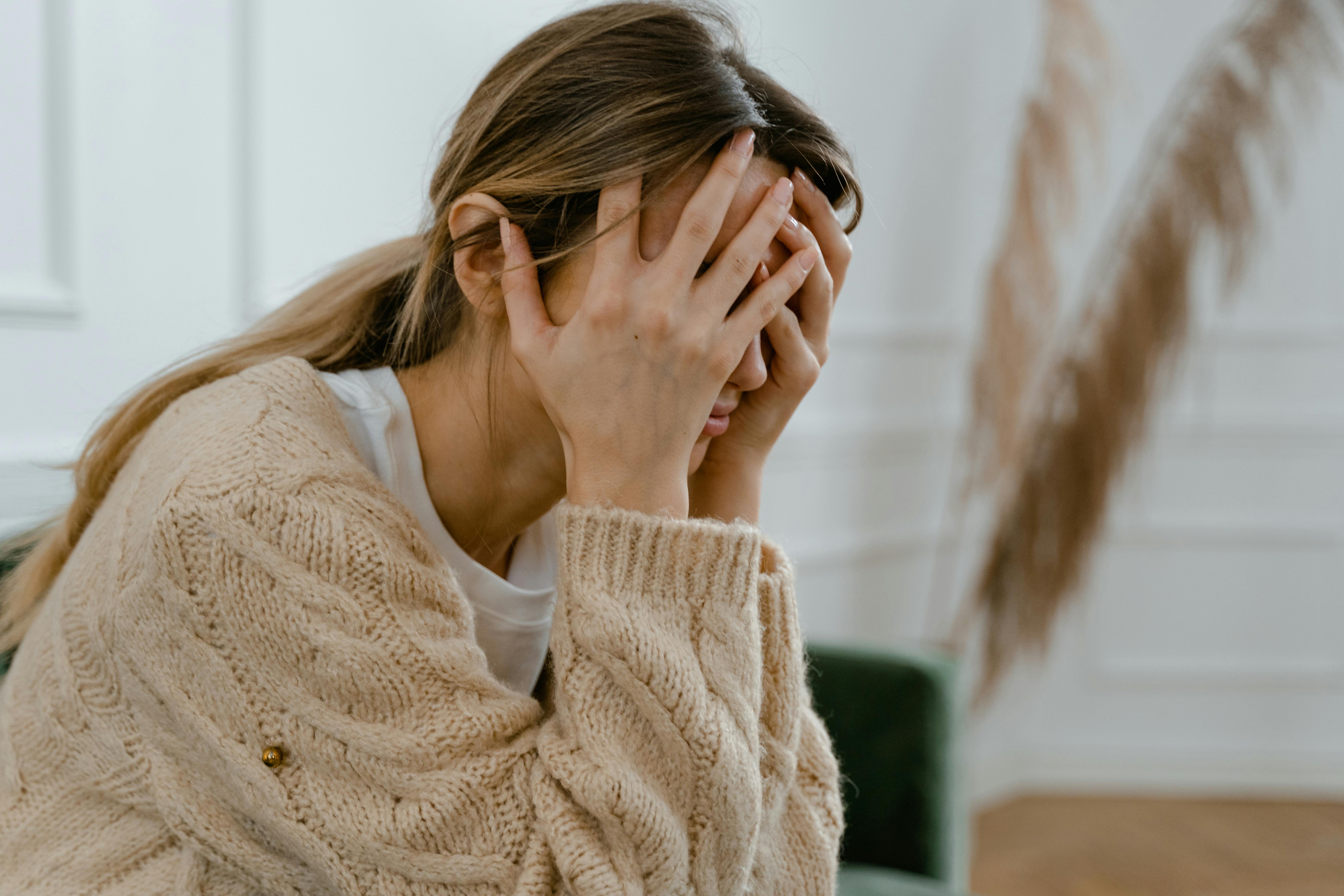 A woman sitting with her hands on her head | Source: Pexels