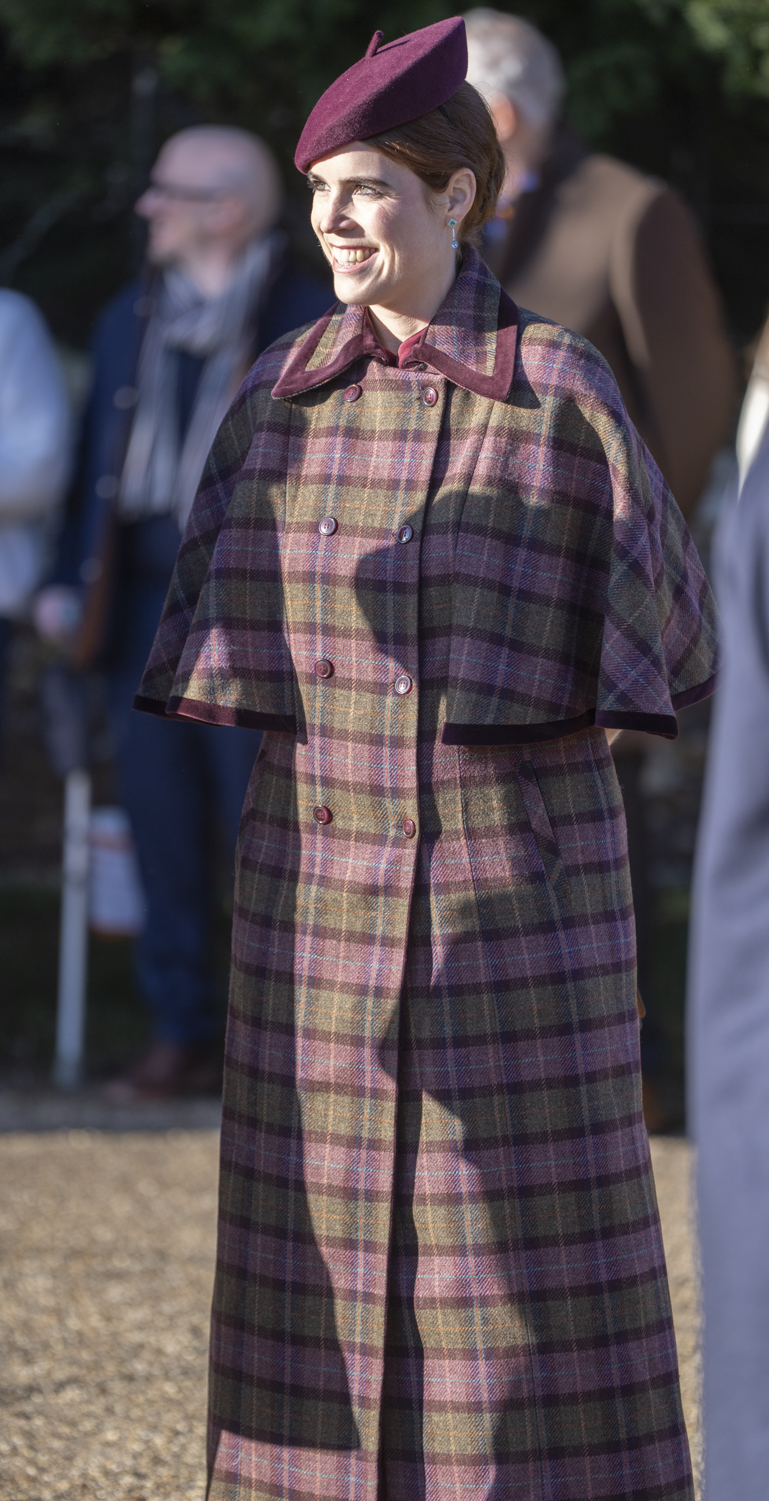 Princess Eugenie attends the Christmas Morning Service at St Mary Magdalene Church in Sandringham, Norfolk, on December 25, 2025, pictured smiling in a plaid coat and burgundy hat.