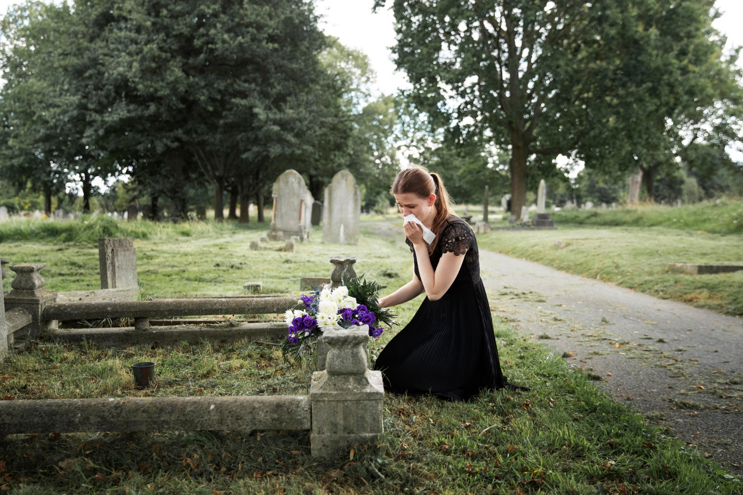 A grieving woman mourning beside a loved one's grave | Source: Freepik
