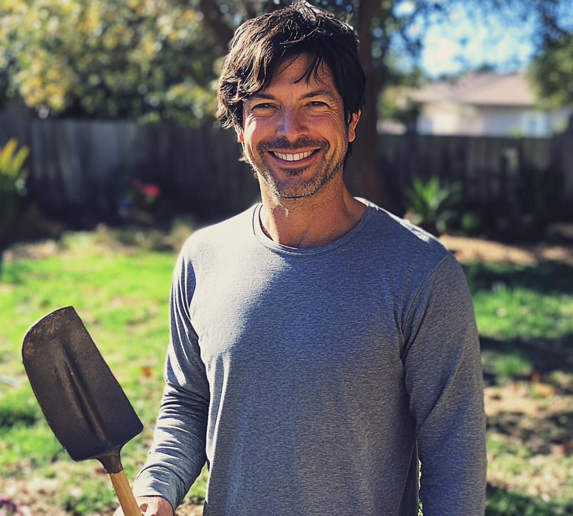 A smiling man holding a shovel | Source: no source