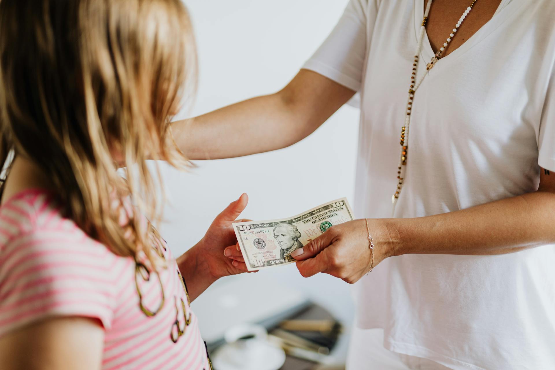 Young kid getting money from an adult | Source: Pexels
