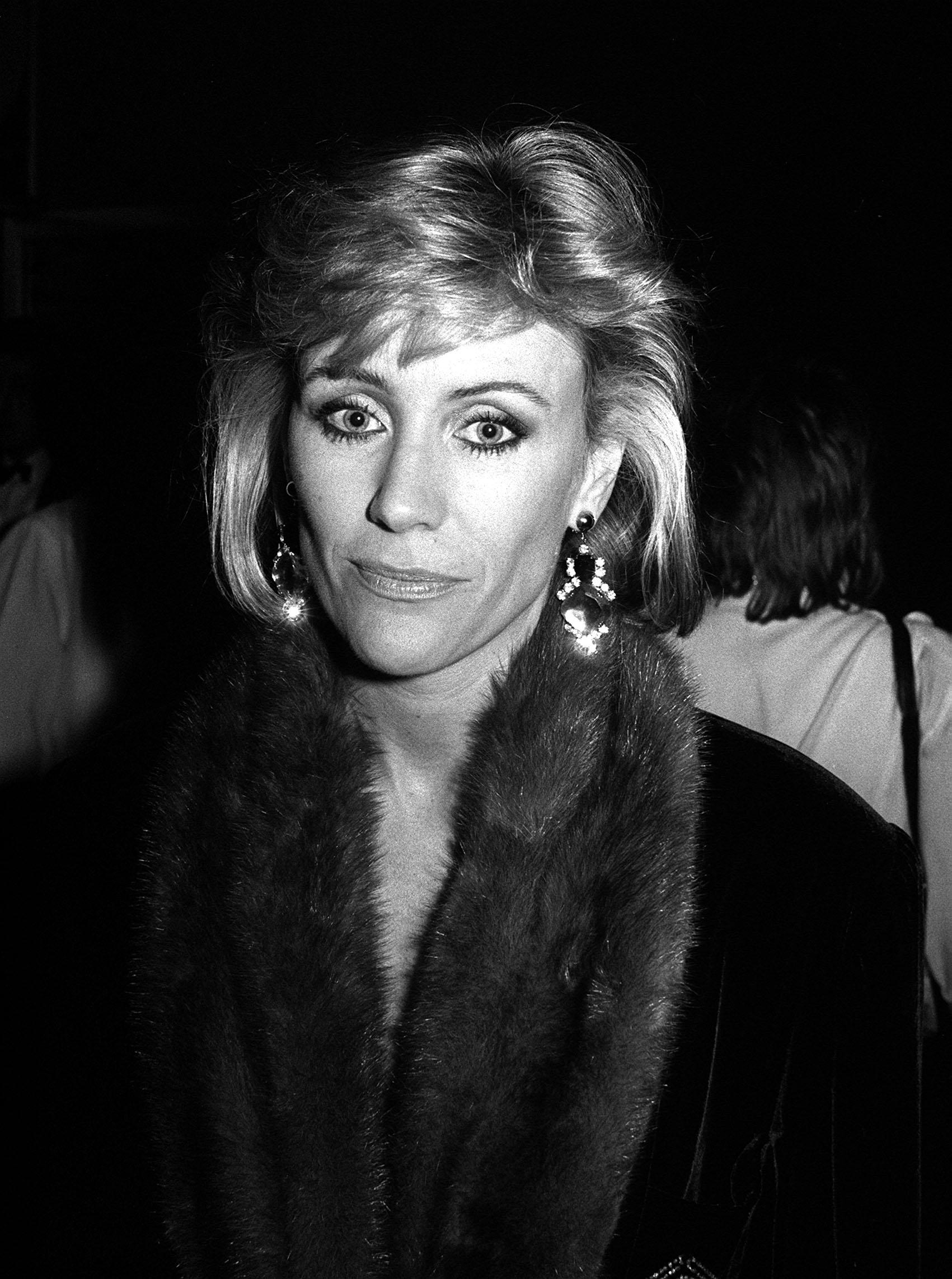 Angie Best is pictured at an evening event, wearing statement earrings and a dark outfit with a fur-trimmed collar, circa 1987 | Source: Getty Images