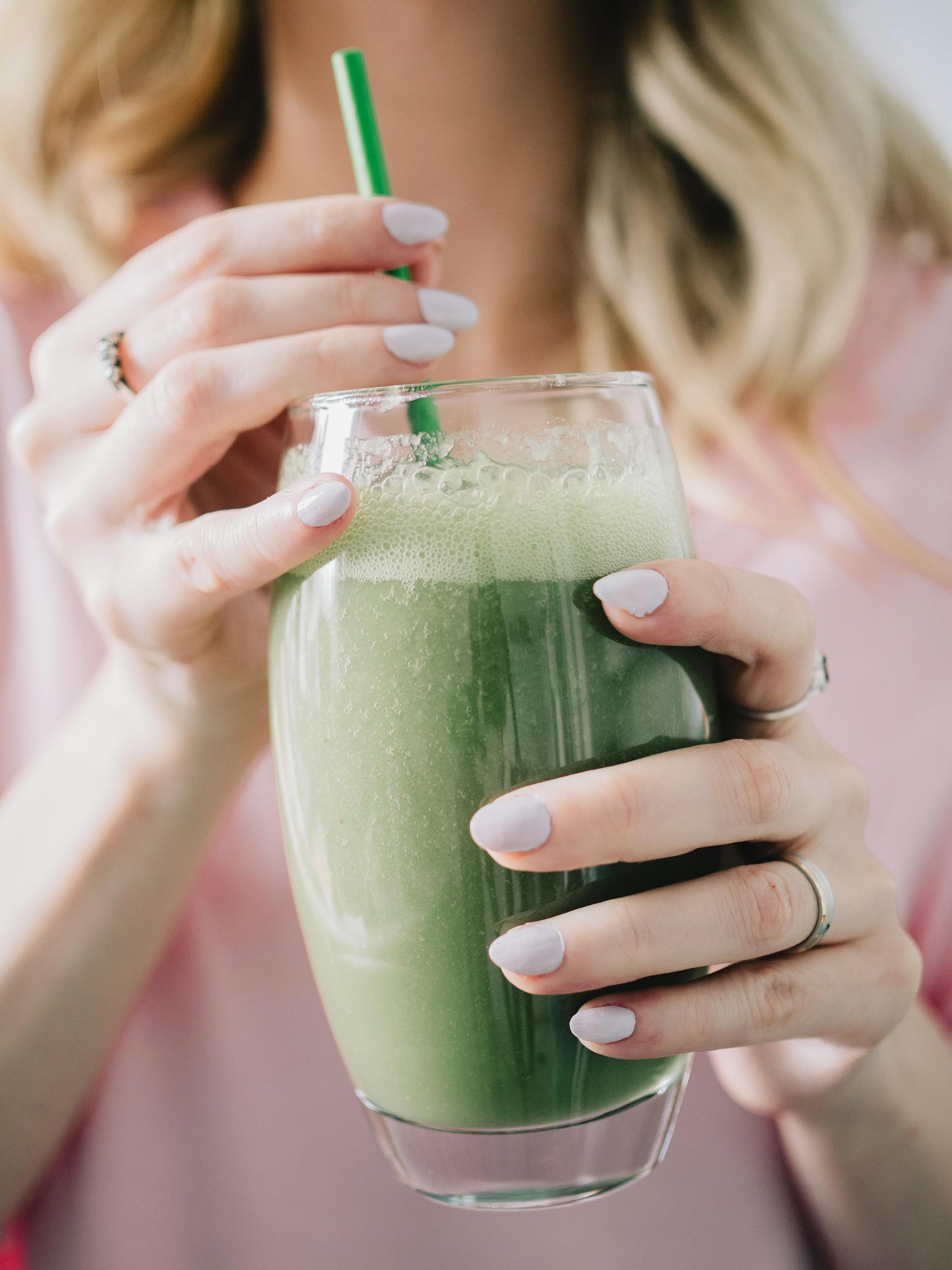 A woman holding a glass of green smoothie | Source: Pexels
