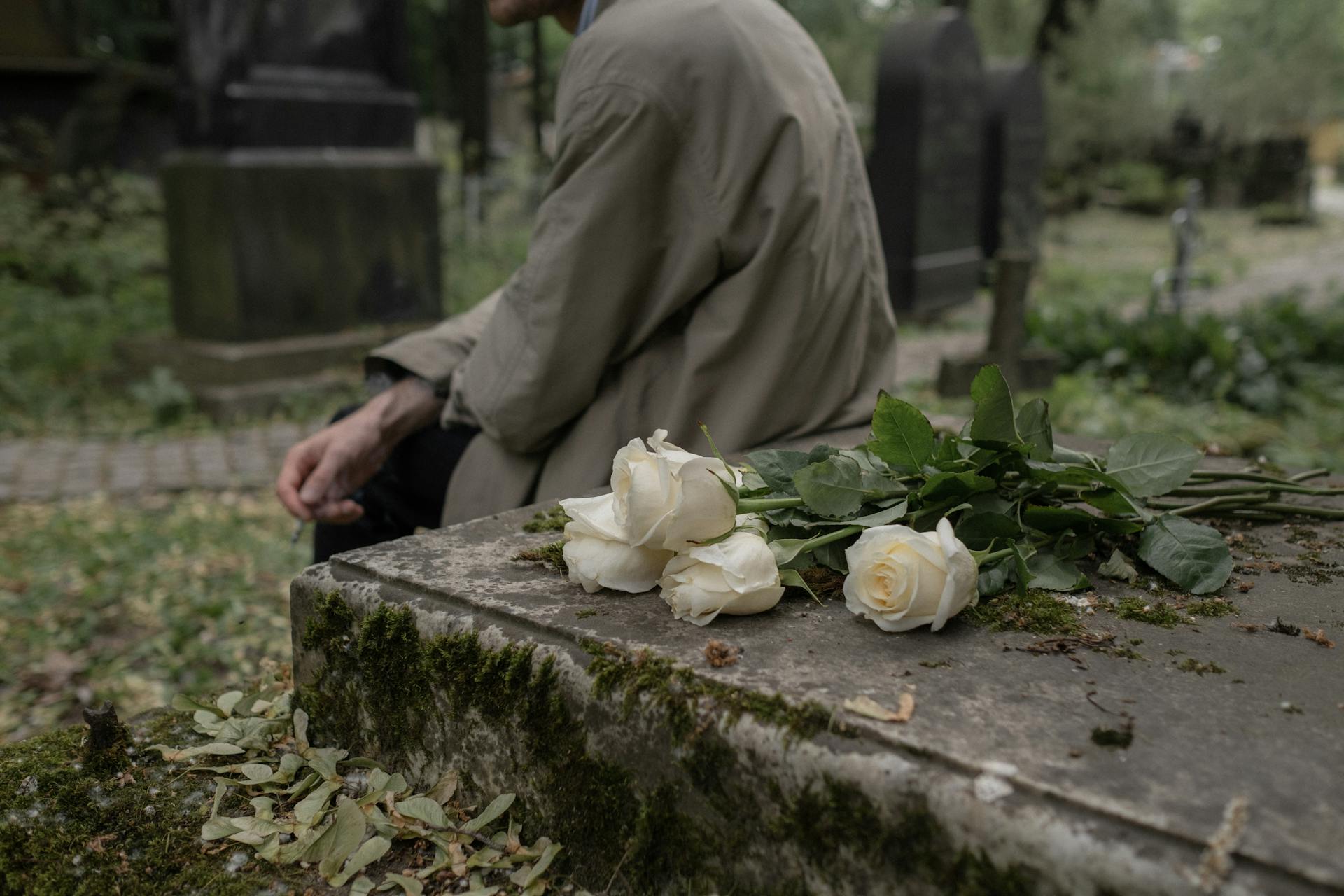 A man sitting beside a grave in a cemetery | Source: Pexels